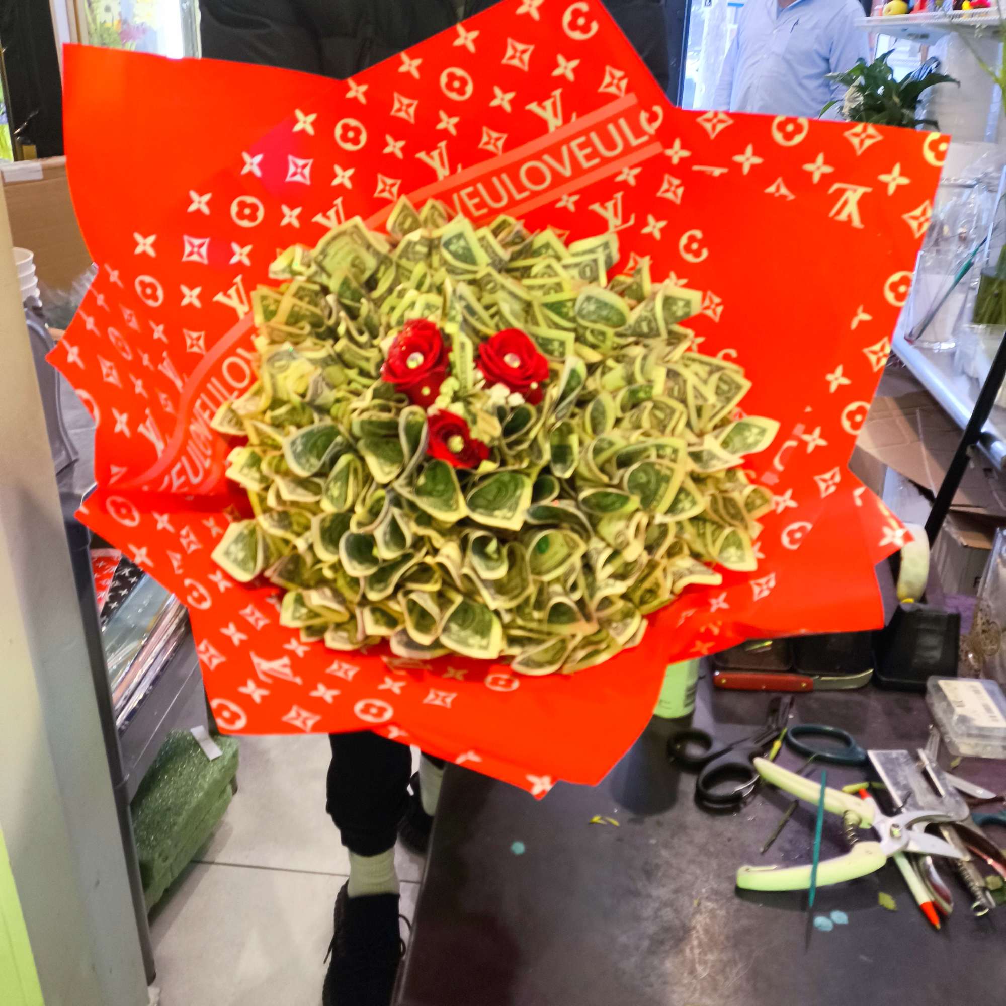Money bouquet with red flowers wrapped in bright red paper
