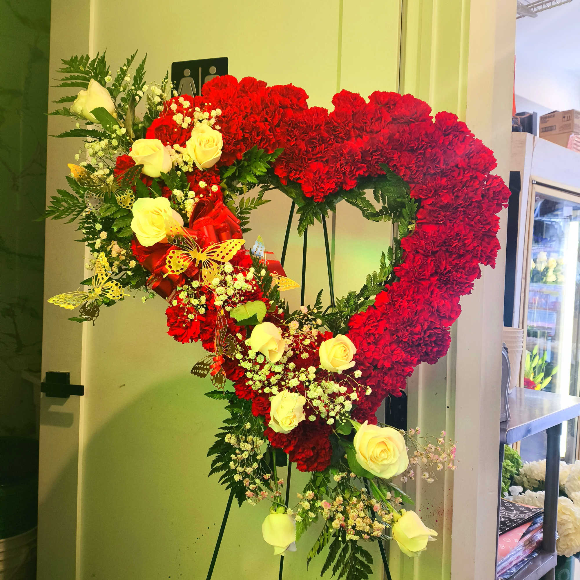 Heart-shaped floral standing arrangement with red carnations and yellow roses