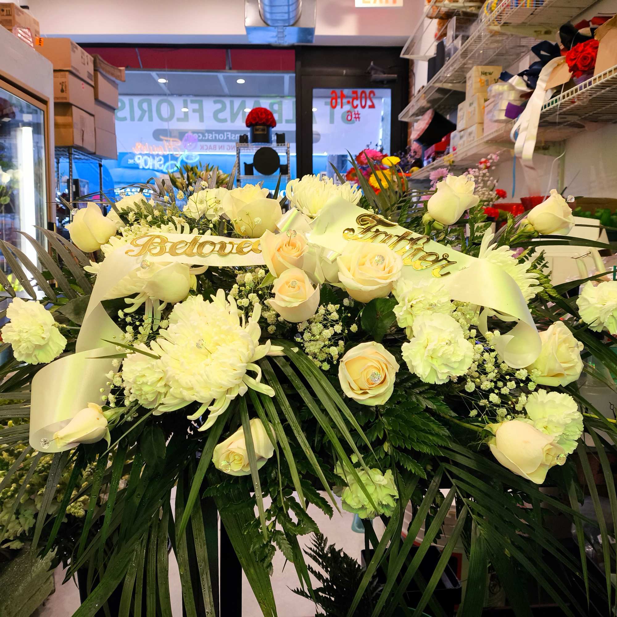 Large white floral spray with roses and ribbon in a shop