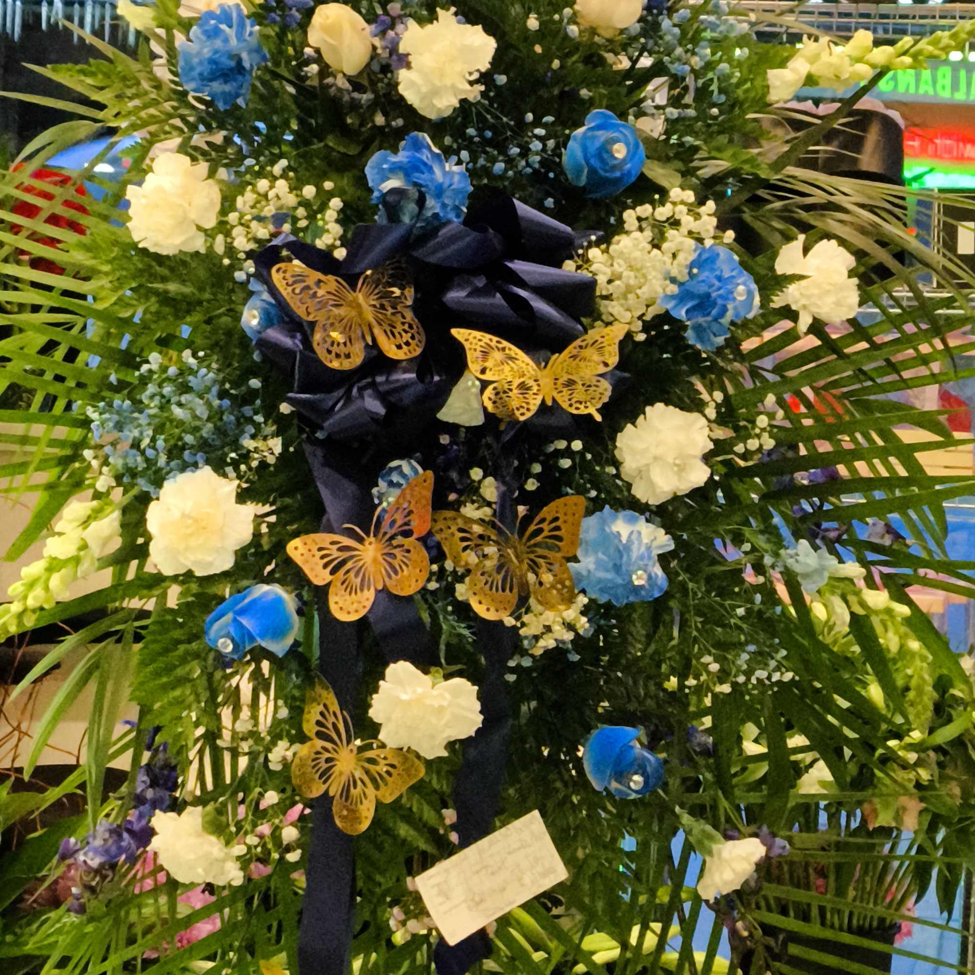Tall floral standing arrangement with blue and white flowers and butterfly accents