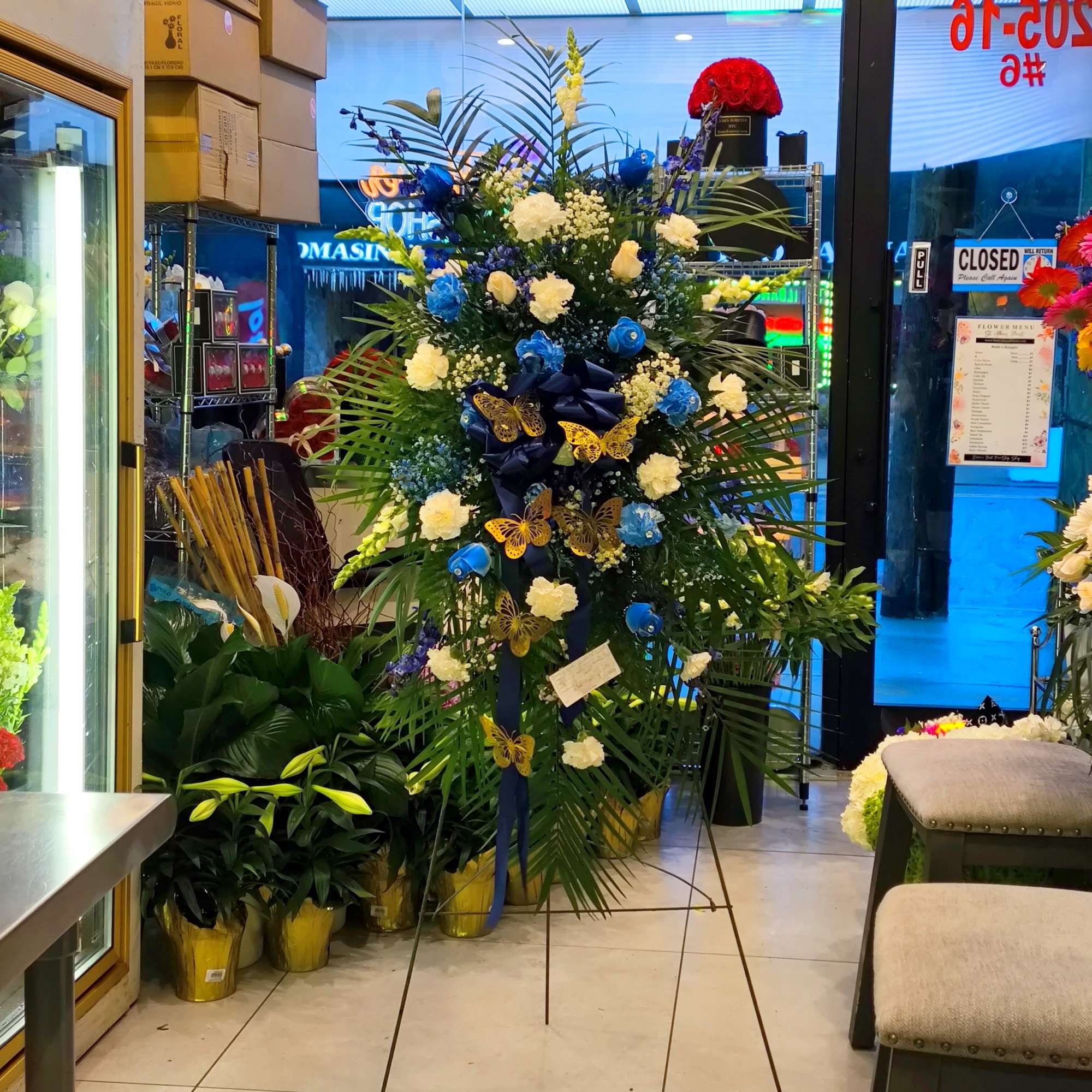 Tall standing floral spray with blue and white flowers and butterfly accents