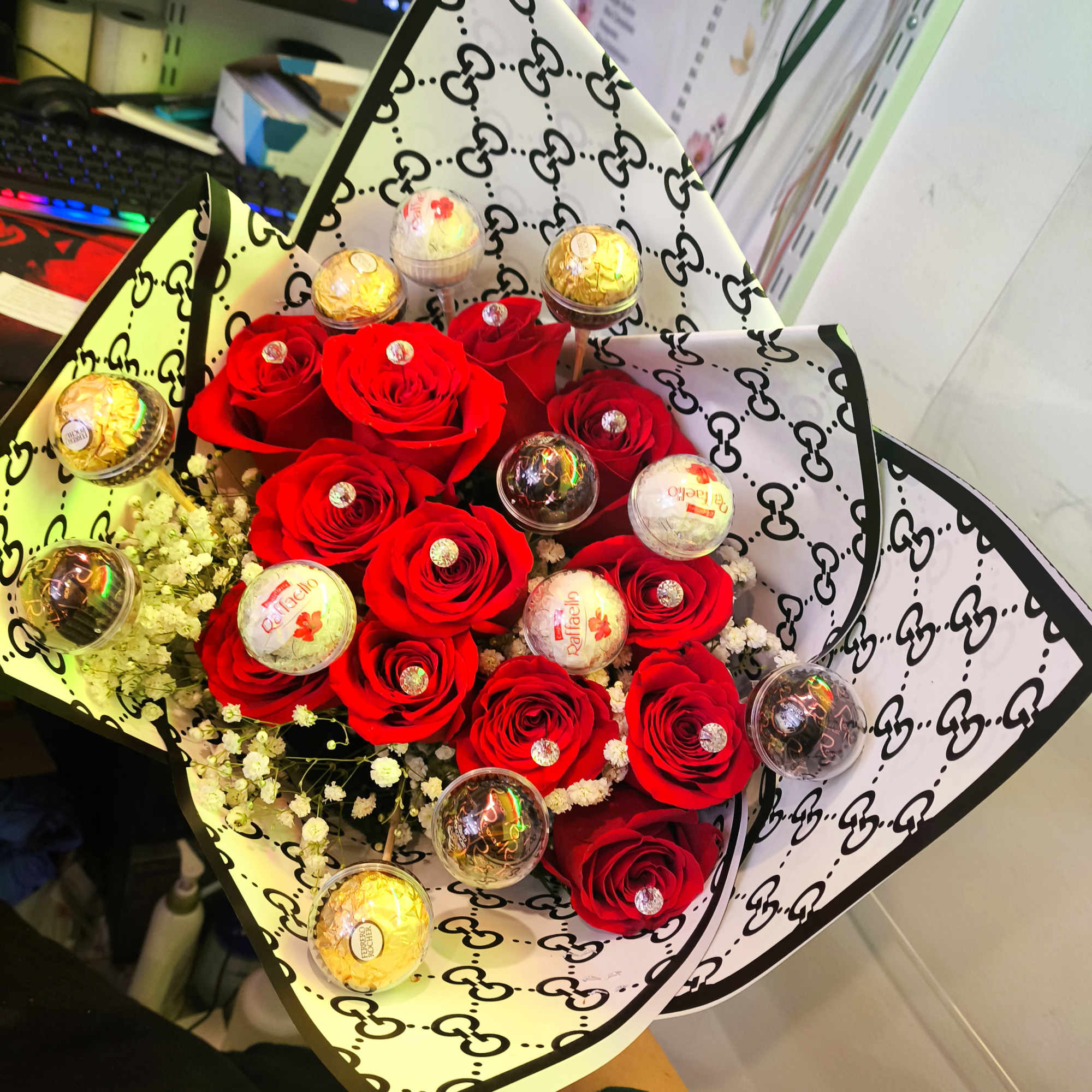 Bouquet of red roses with small wrapped chocolates in patterned paper