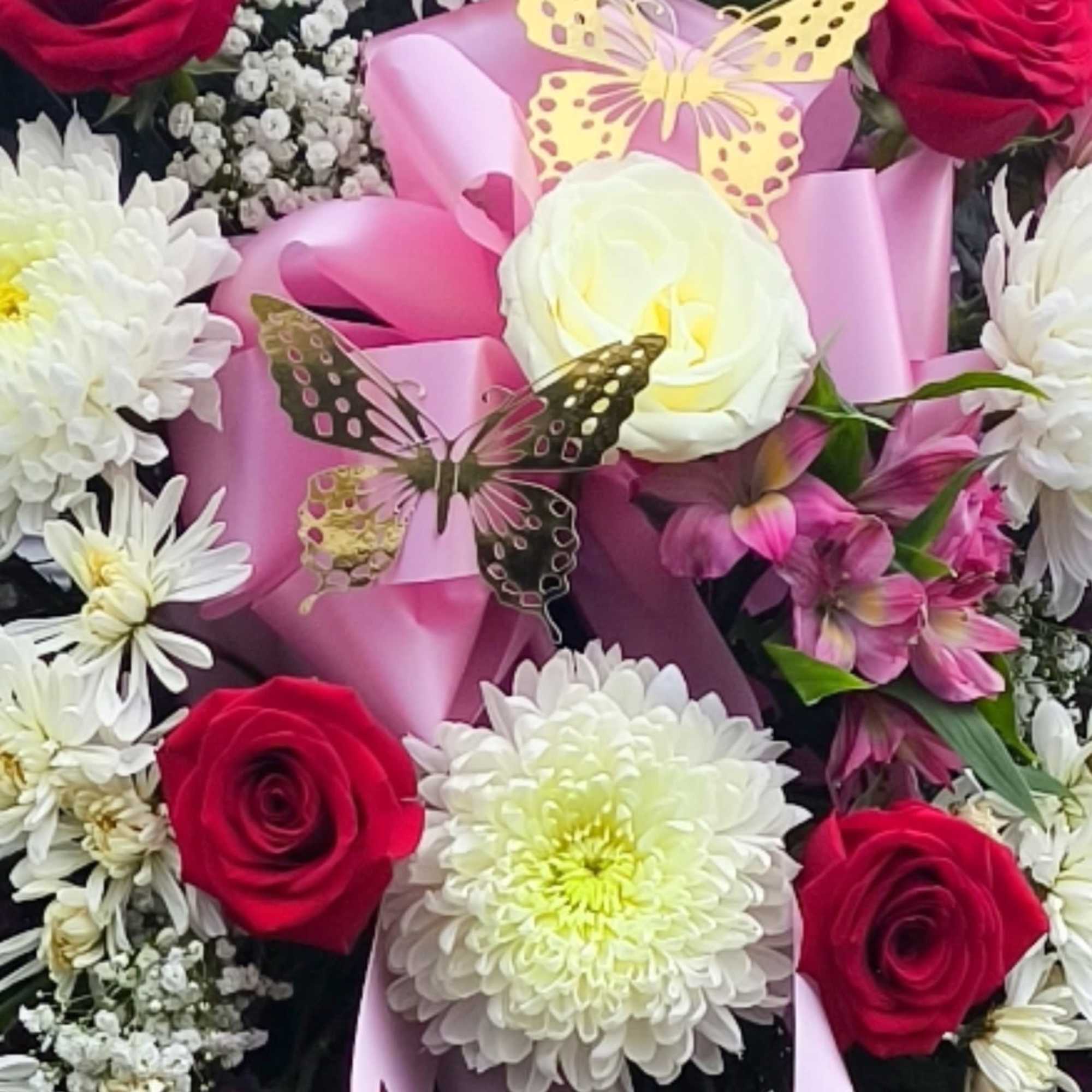 Bouquet of red and white flowers with pink ribbon and butterfly accents