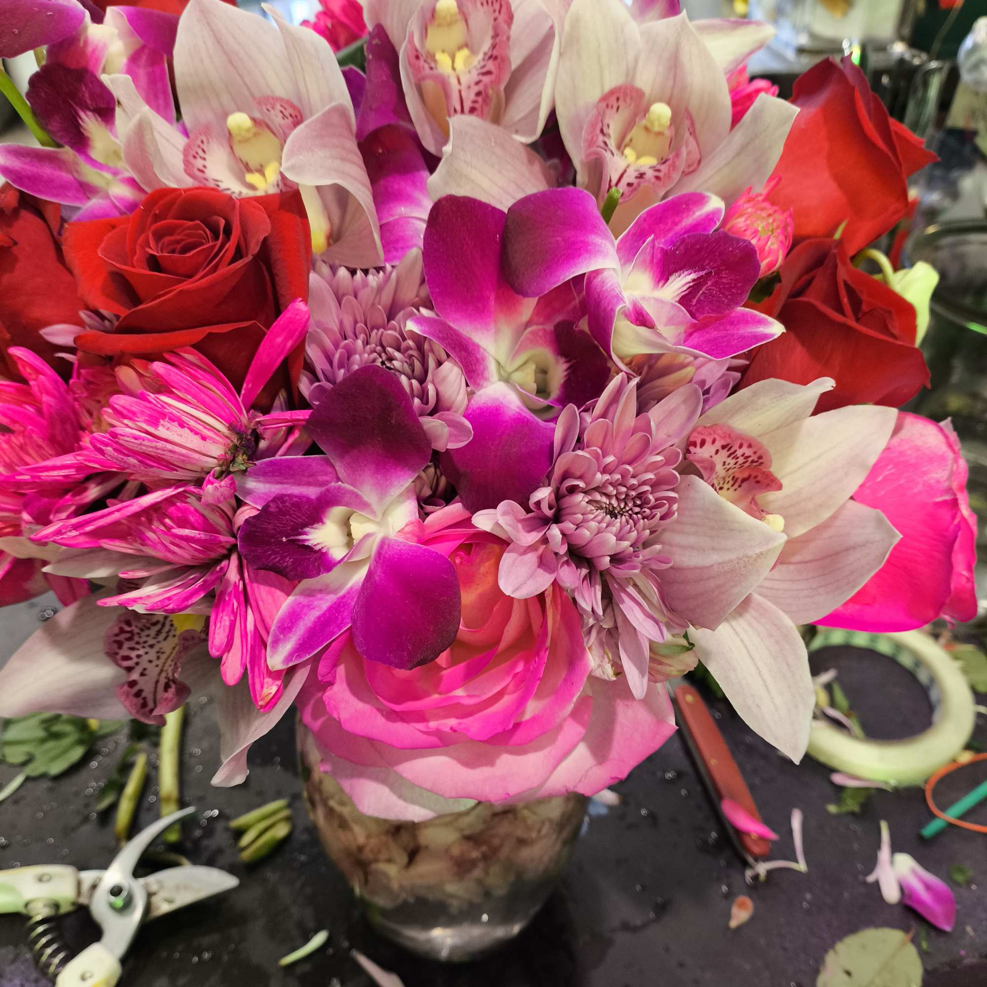 Pink and red bouquet with orchids, roses, and chrysanthemums in a glass vase