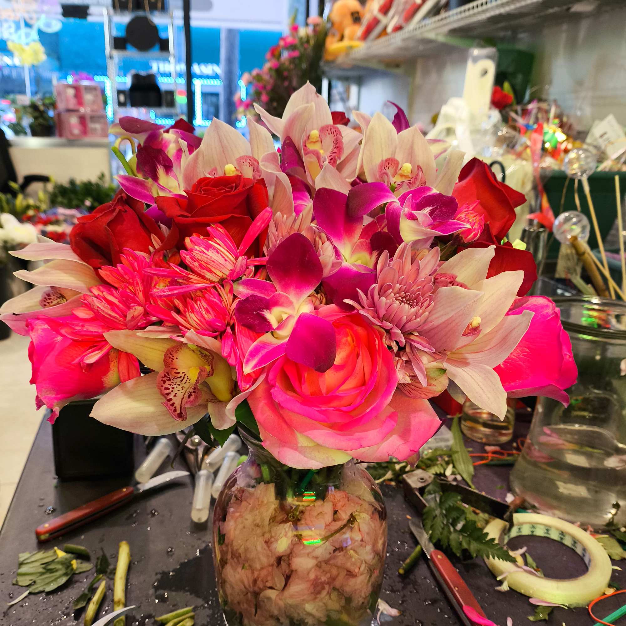 Bright pink and red bouquet with orchids and roses in a glass vase