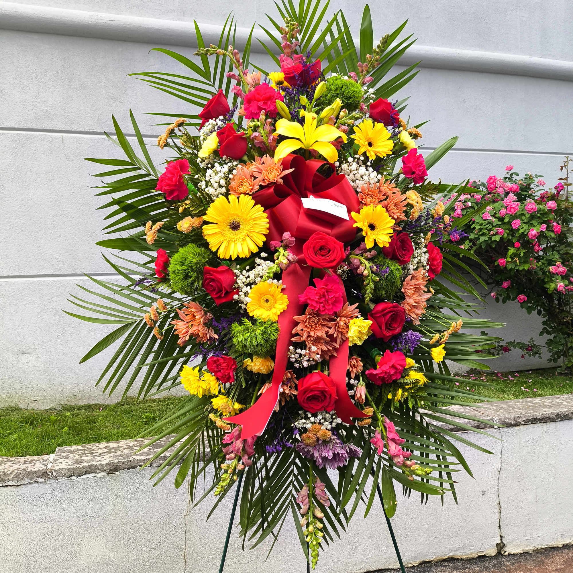 Large standing floral spray with red, yellow, and pink flowers