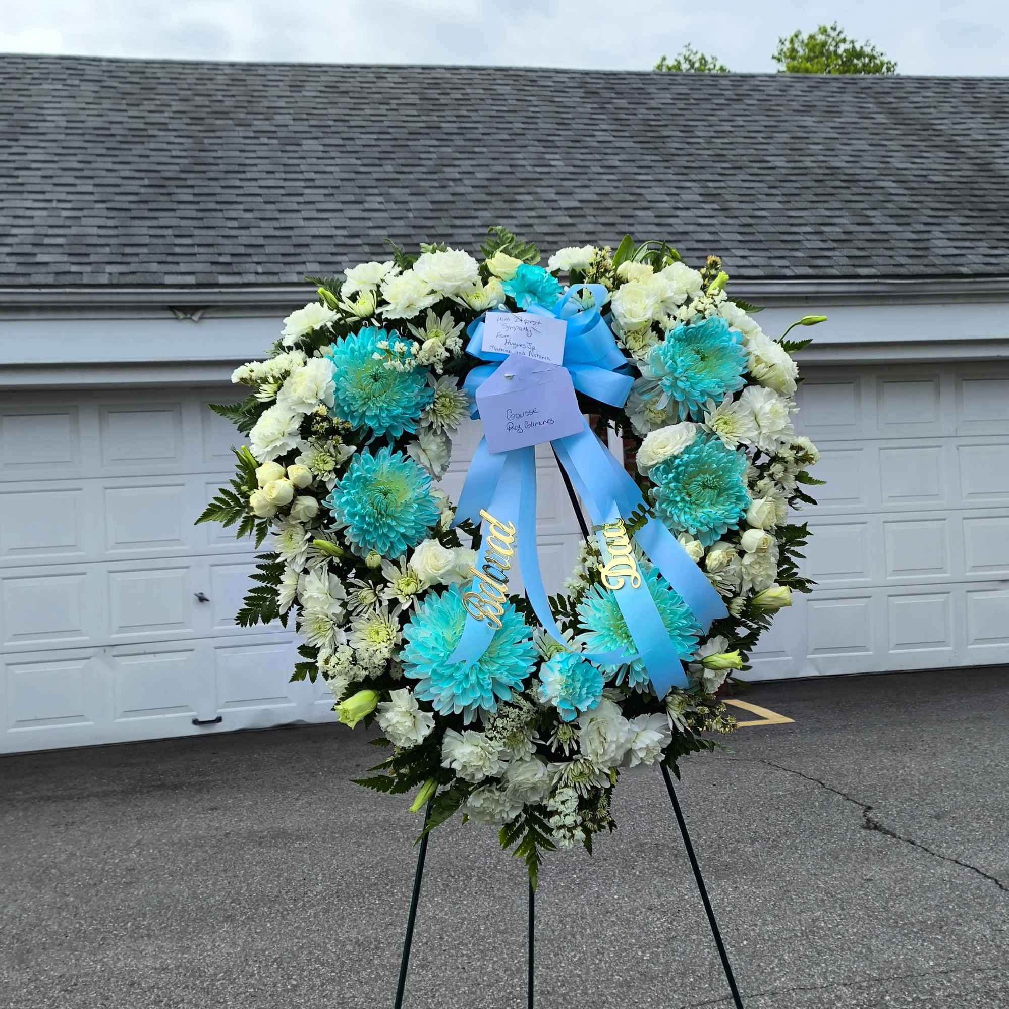Heart-shaped funeral wreath of white and turquoise flowers on an easel
