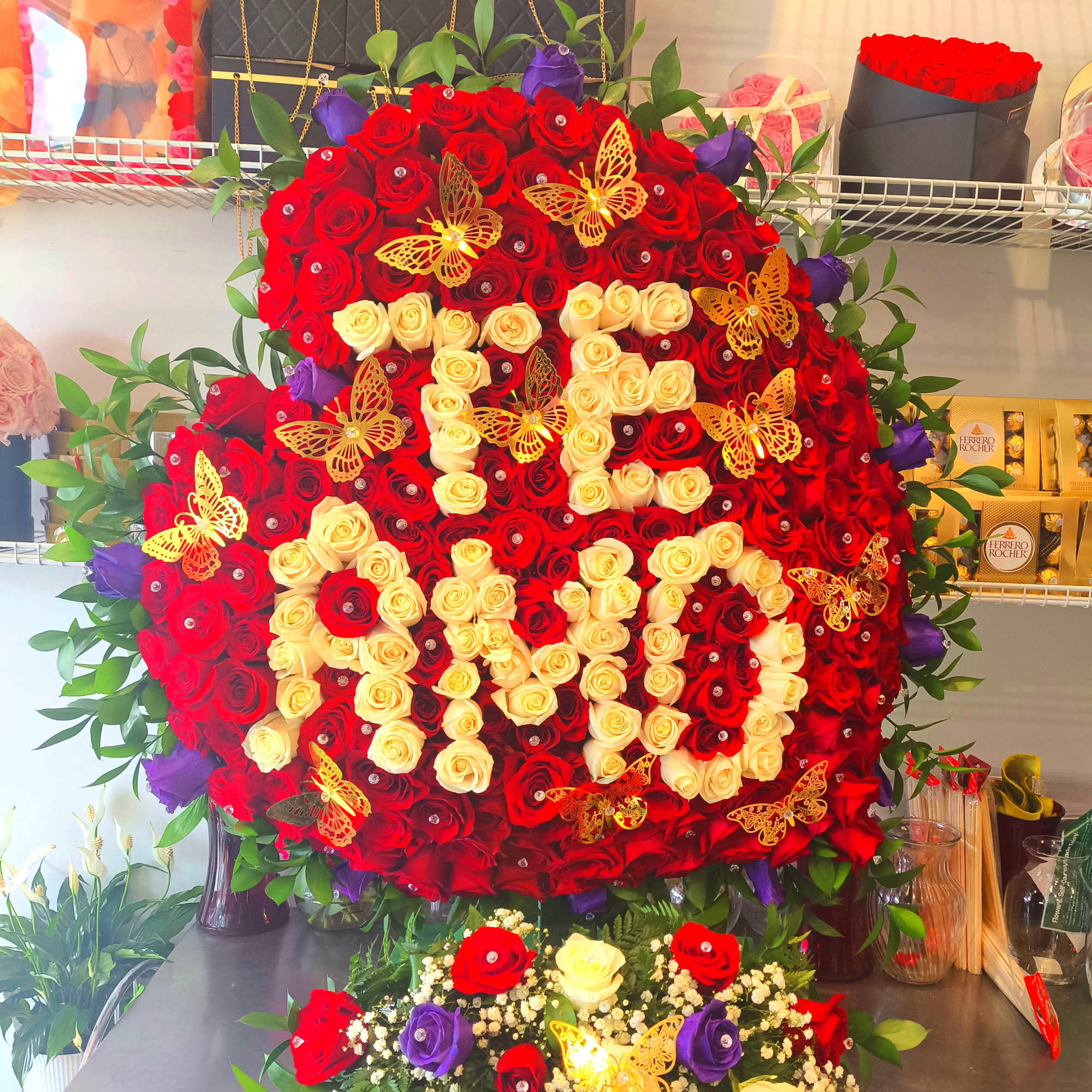 Large heart-shaped rose arrangement with red, cream, and purple roses