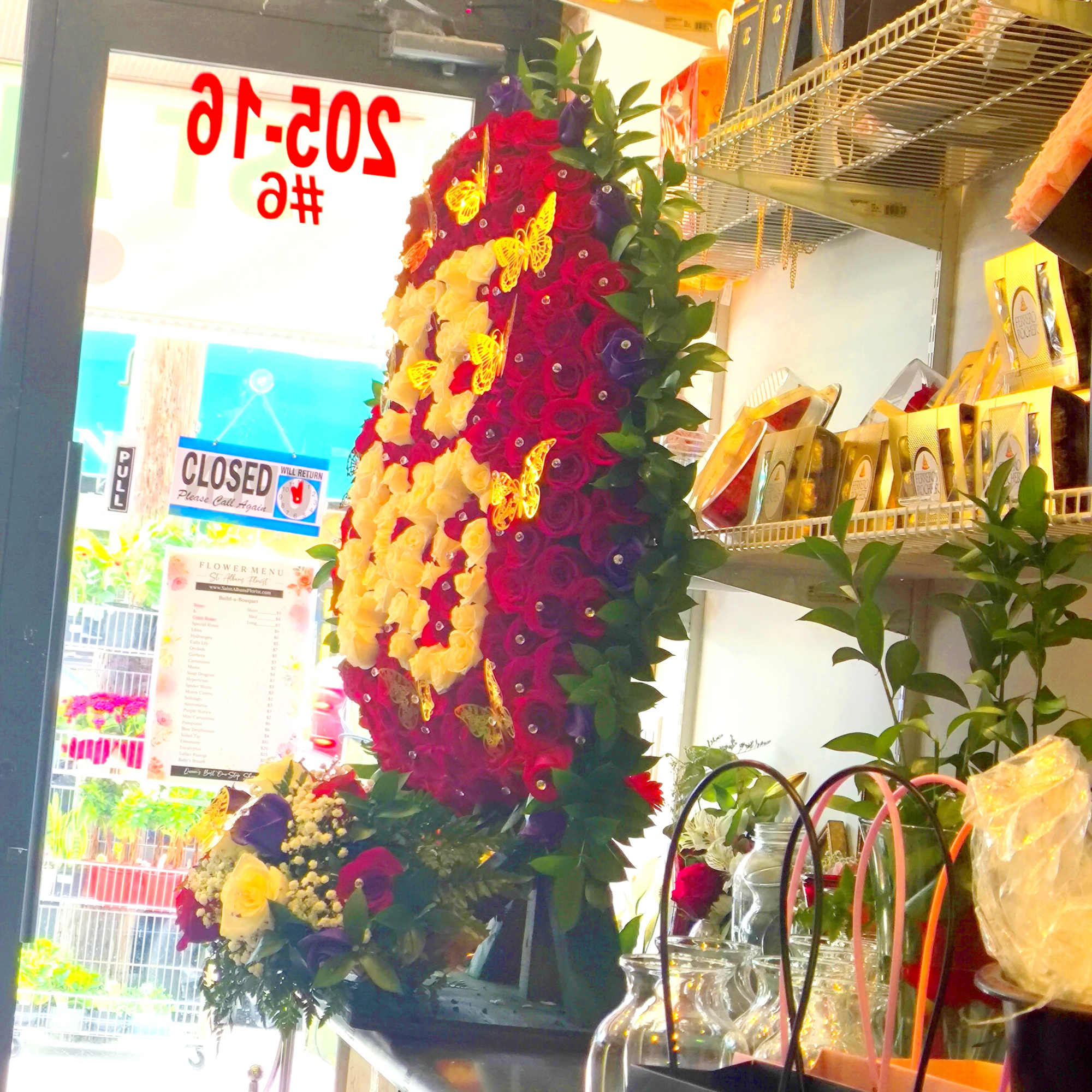 Tall floral standing display with red, yellow, and purple roses