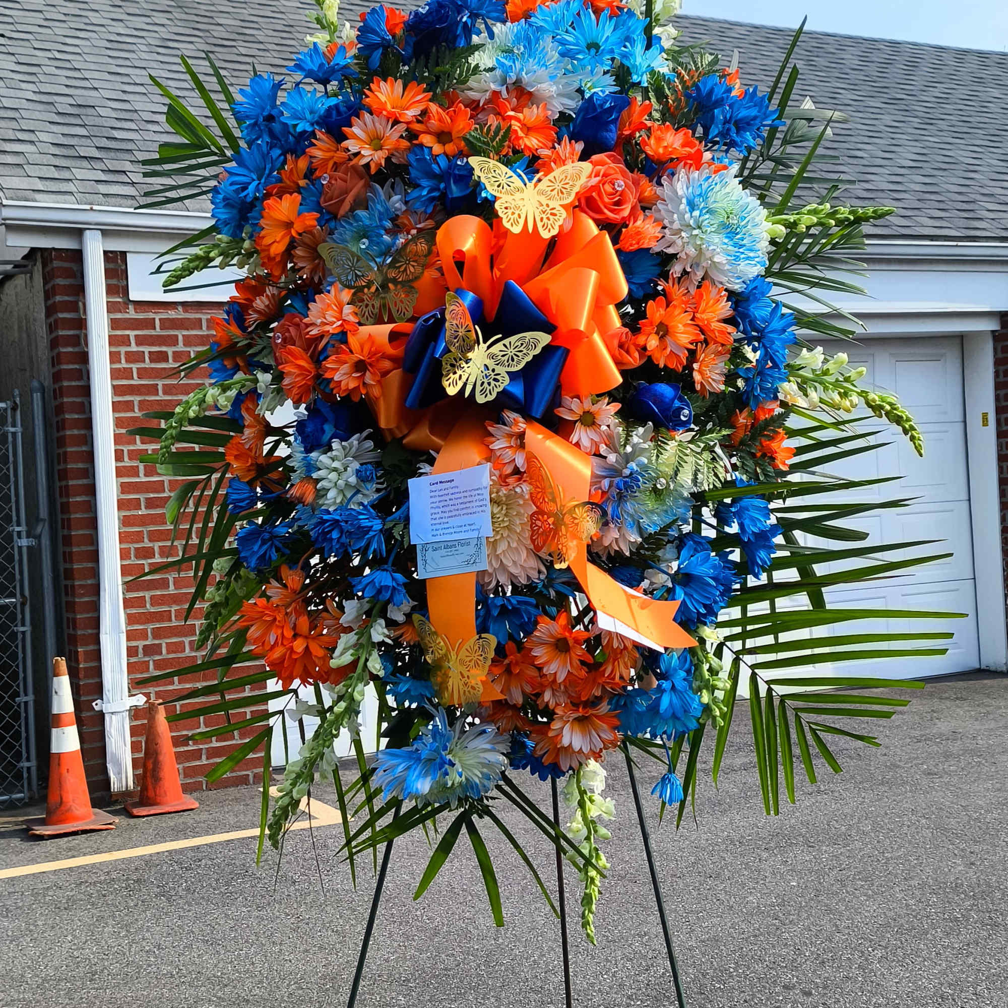 Large standing floral wreath with blue, orange, and white flowers on an easel