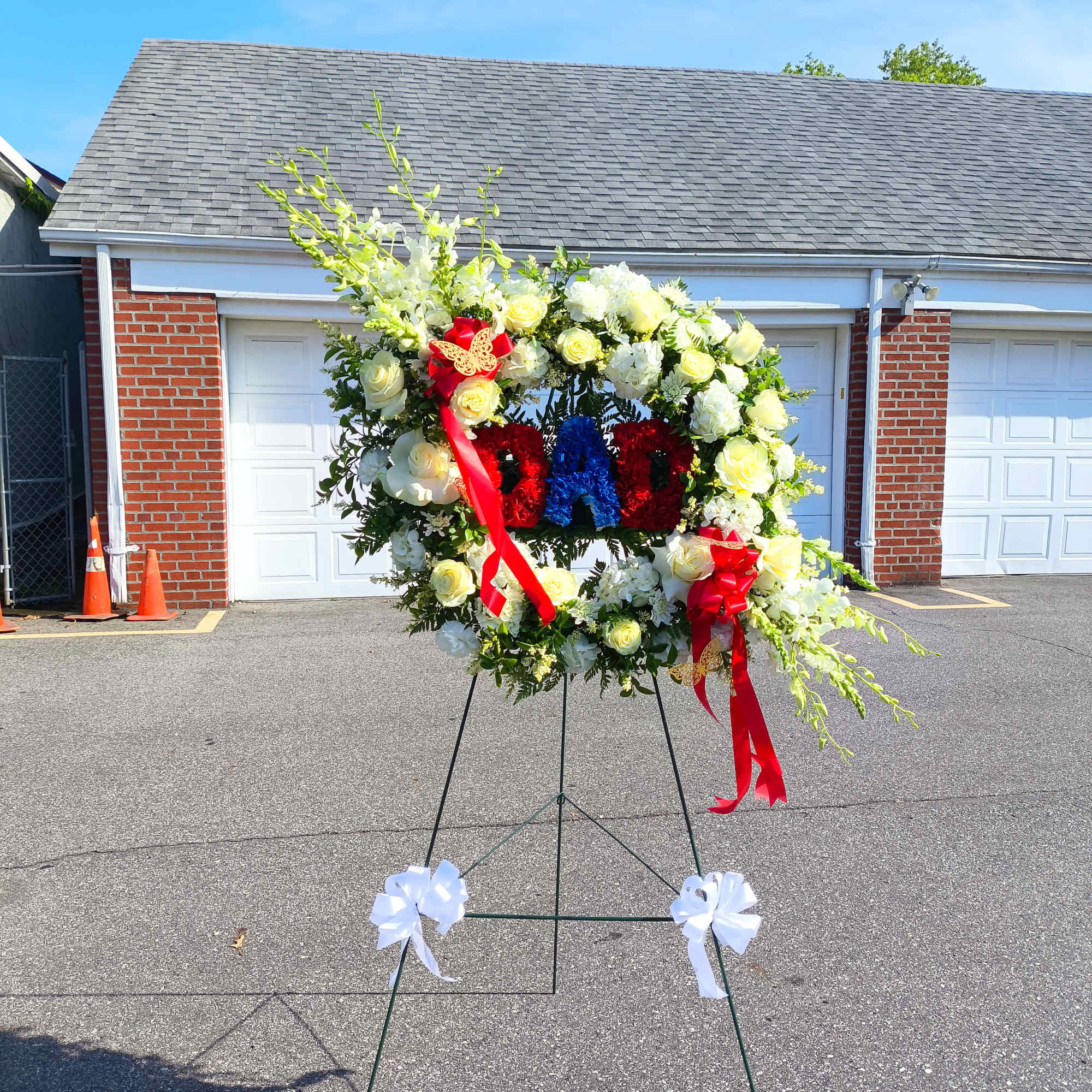 Large floral wreath on an easel with red, white, and blue flowers