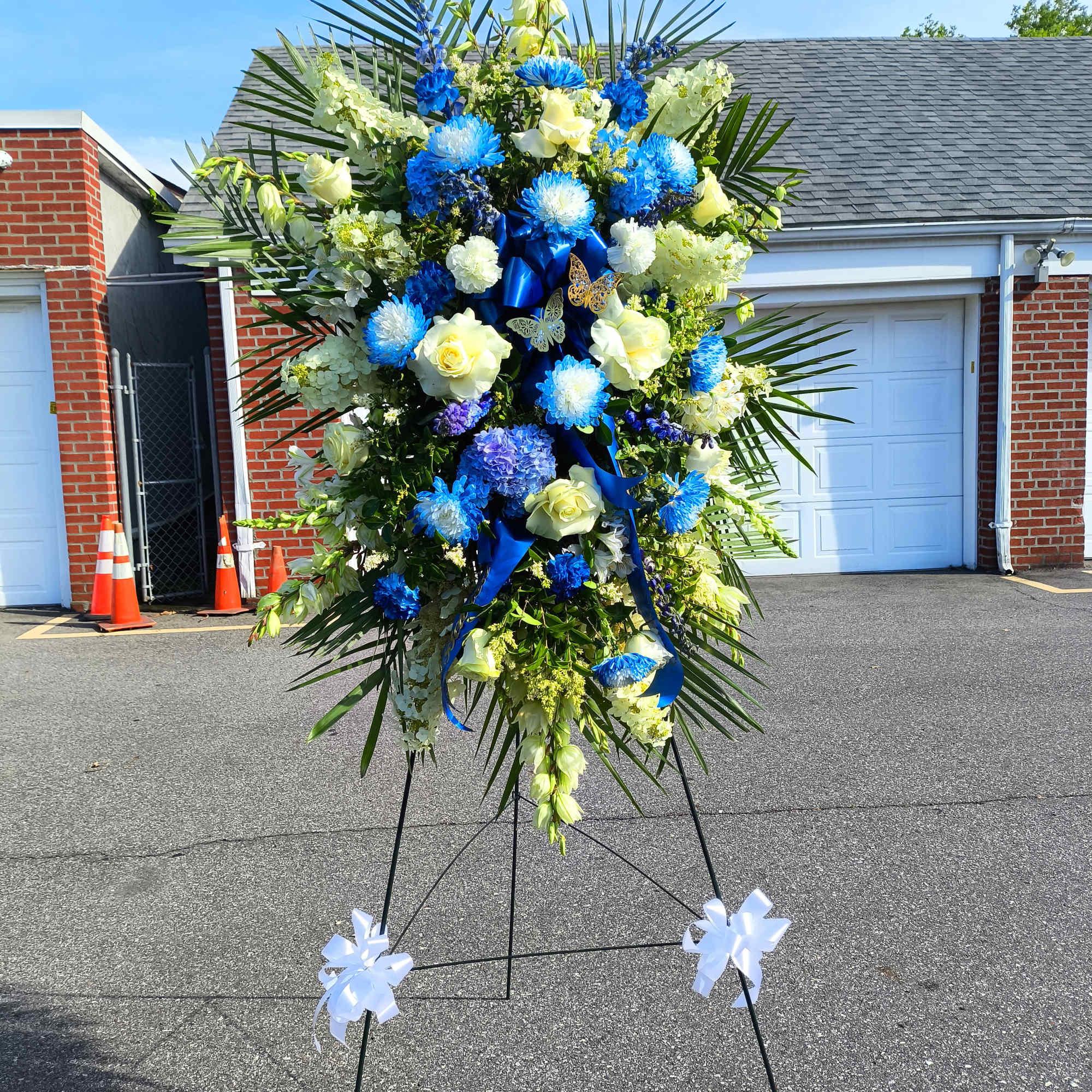 Large standing floral spray with blue and white flowers on an easel