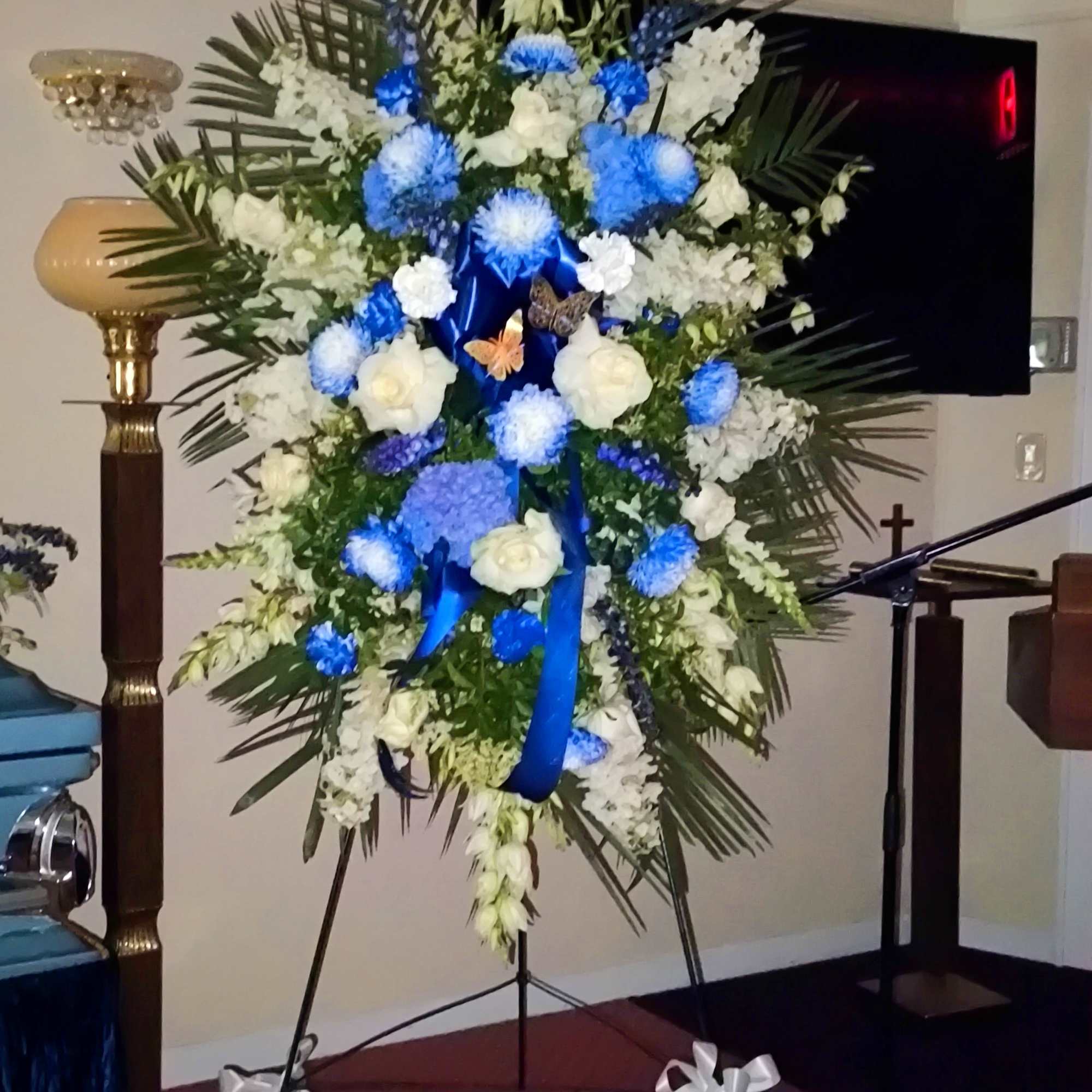 Large standing floral spray with white and blue flowers on an easel