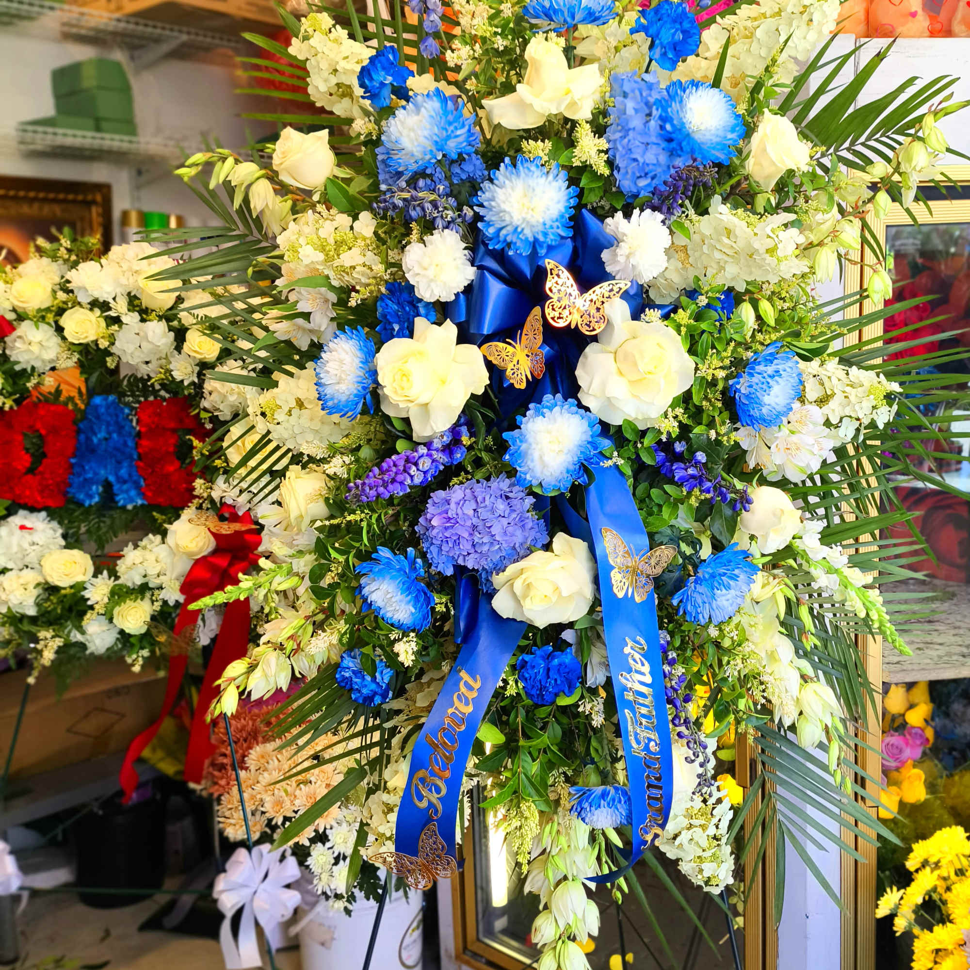 Large standing floral spray with blue and white flowers on an easel, photo 3 of 4