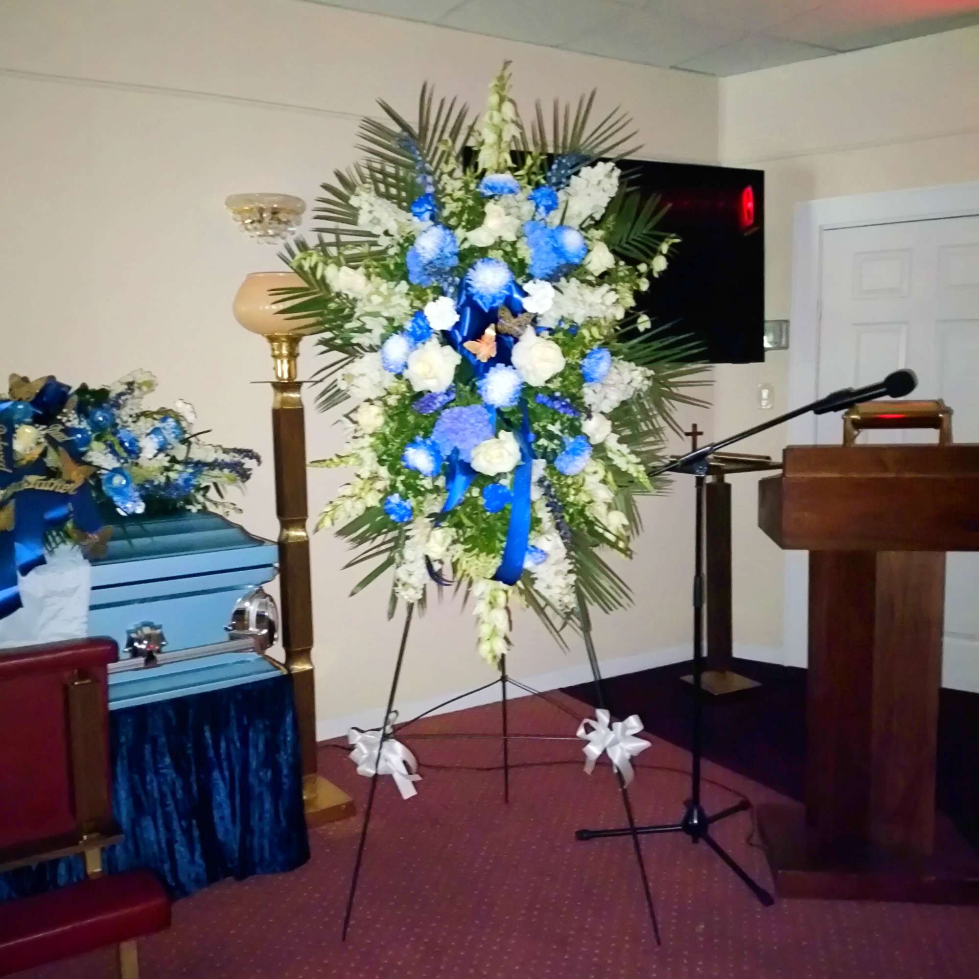 Tall blue and white funeral spray on an easel