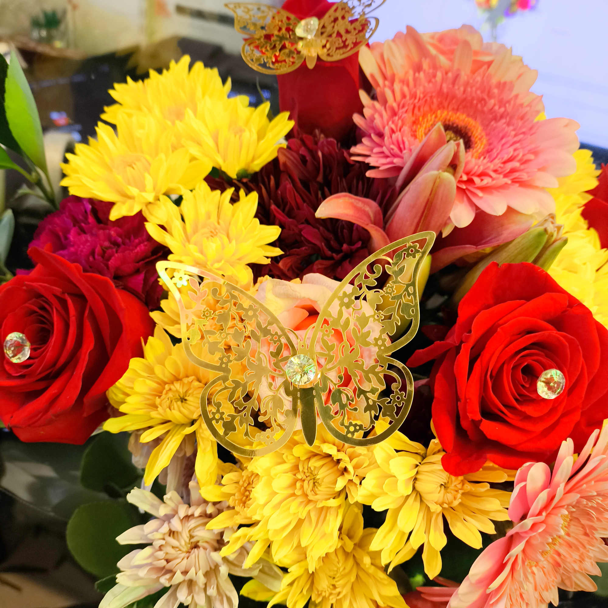 Bouquet of red roses, yellow chrysanthemums, and pink gerbera daisies with butterfly picks