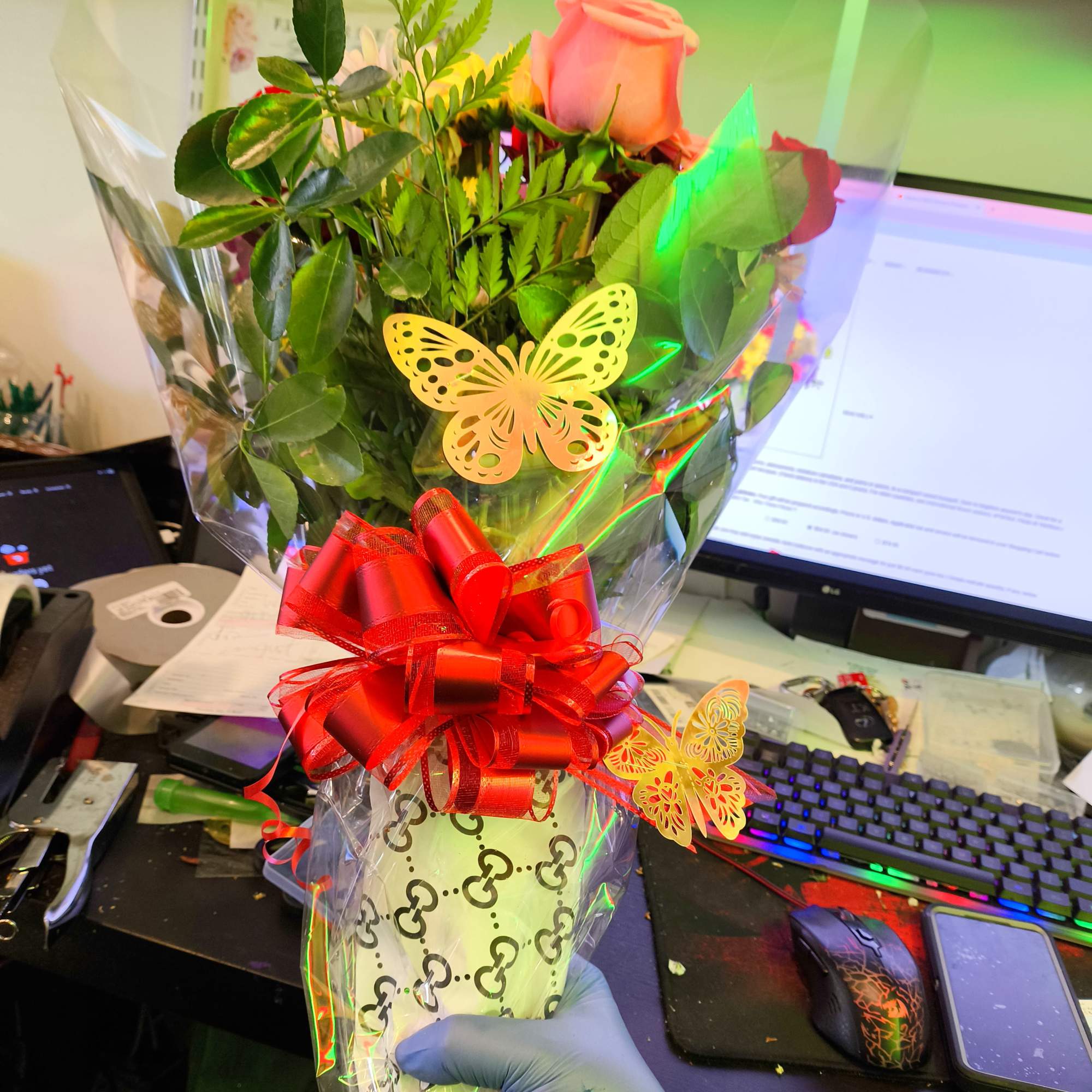 Wrapped bouquet of pink and red roses with a red bow