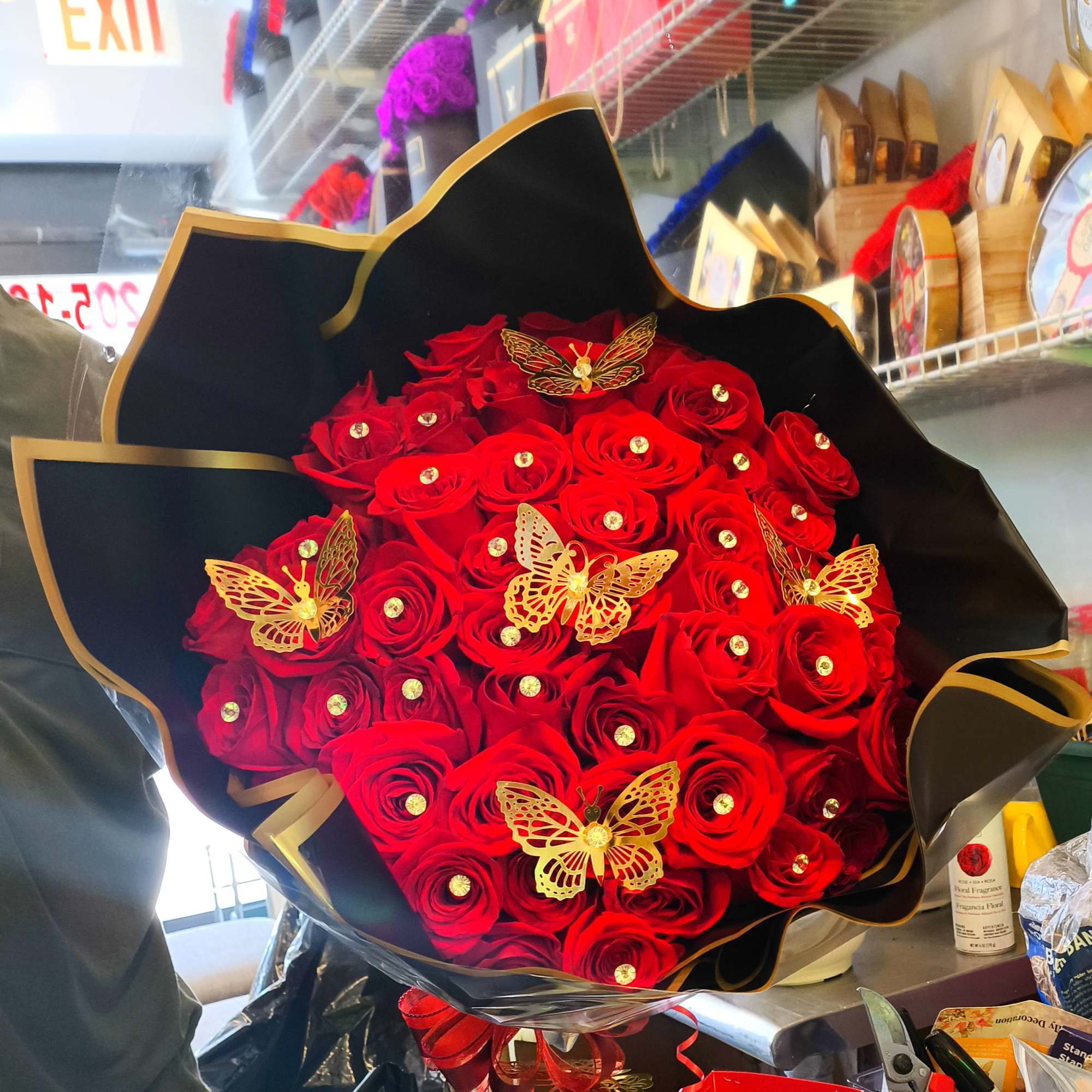 Bouquet of red roses with gold butterfly decorations in black wrap