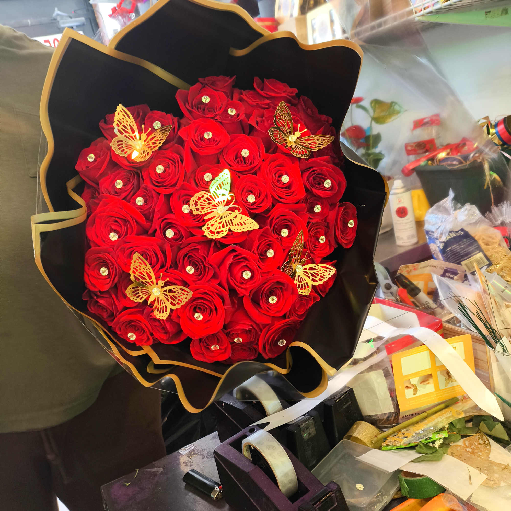 Bouquet of red roses in black wrapping with gold butterfly accents