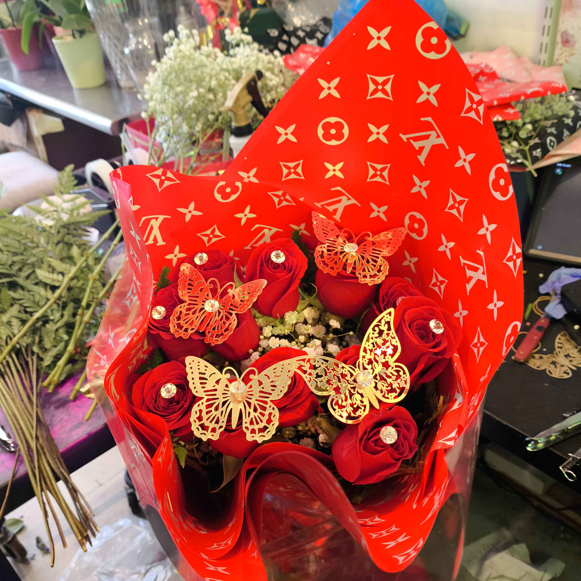 A dozen long stem red roses with diamonds and gold butterflies wrapped