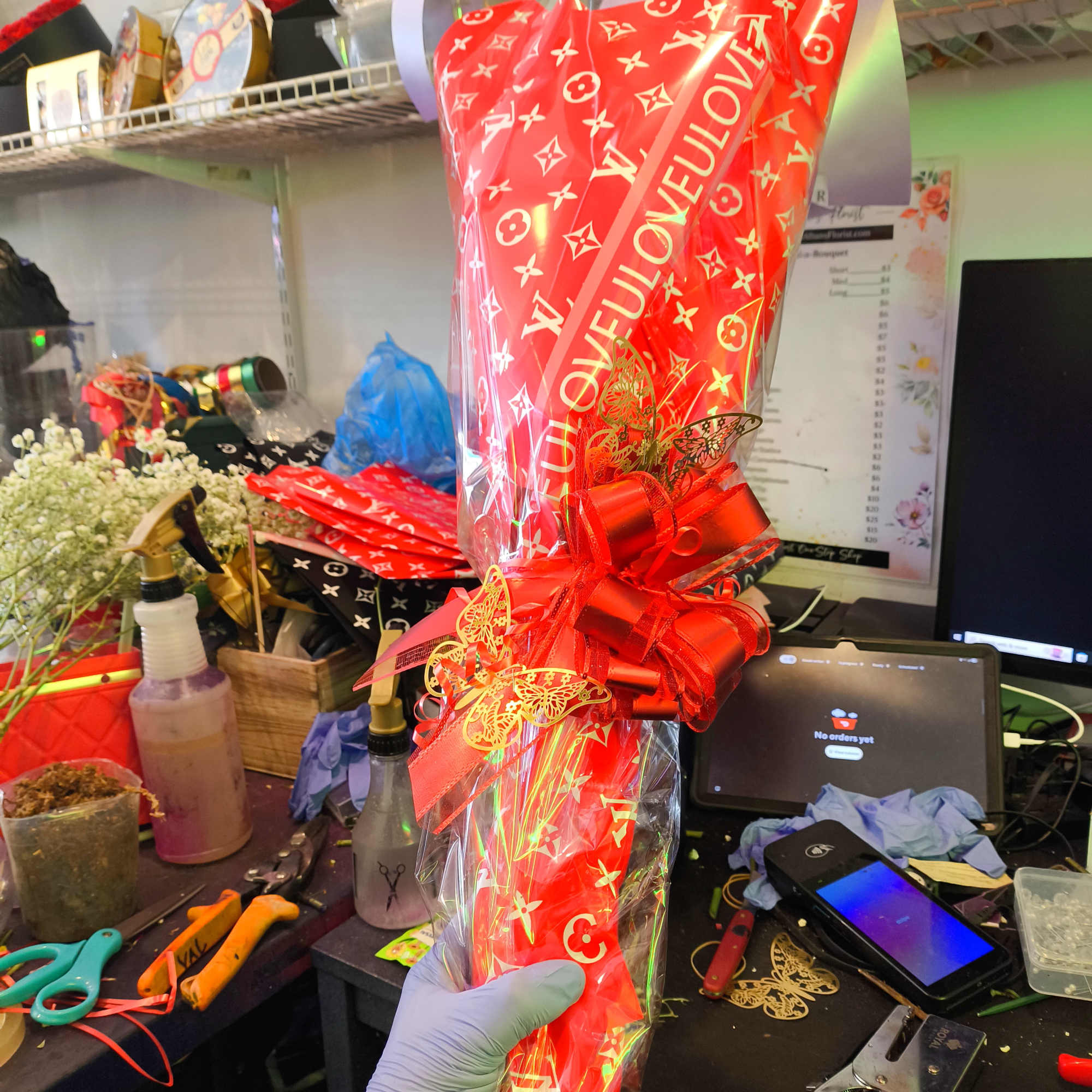 Hand holding a red wrapped bouquet with a large bow