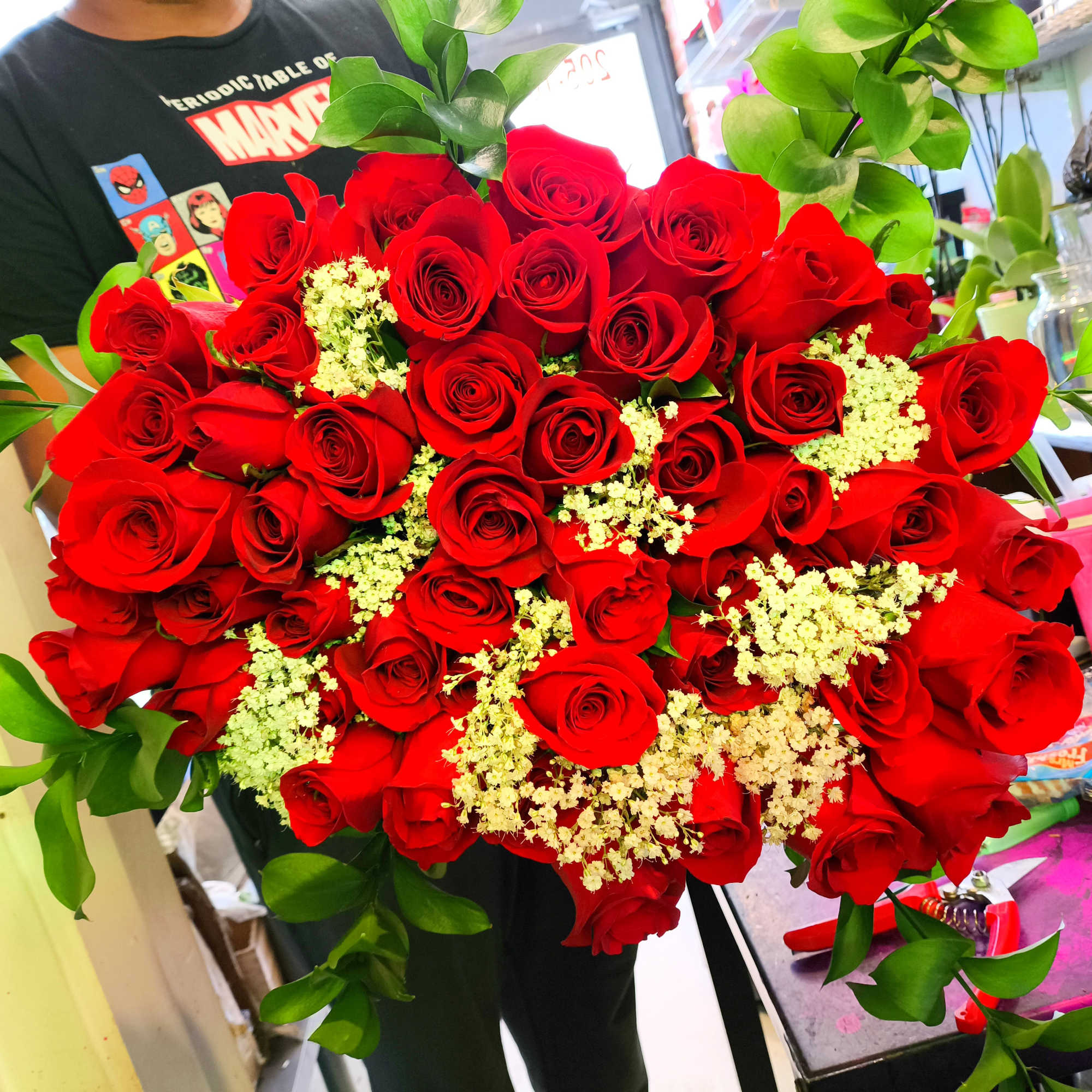 Large bouquet of red roses with white filler flowers and greenery