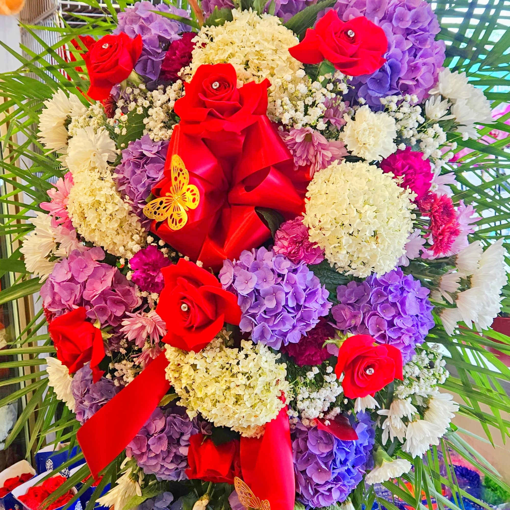 Large bouquet of red roses, purple hydrangeas, and white daisies with red ribbon