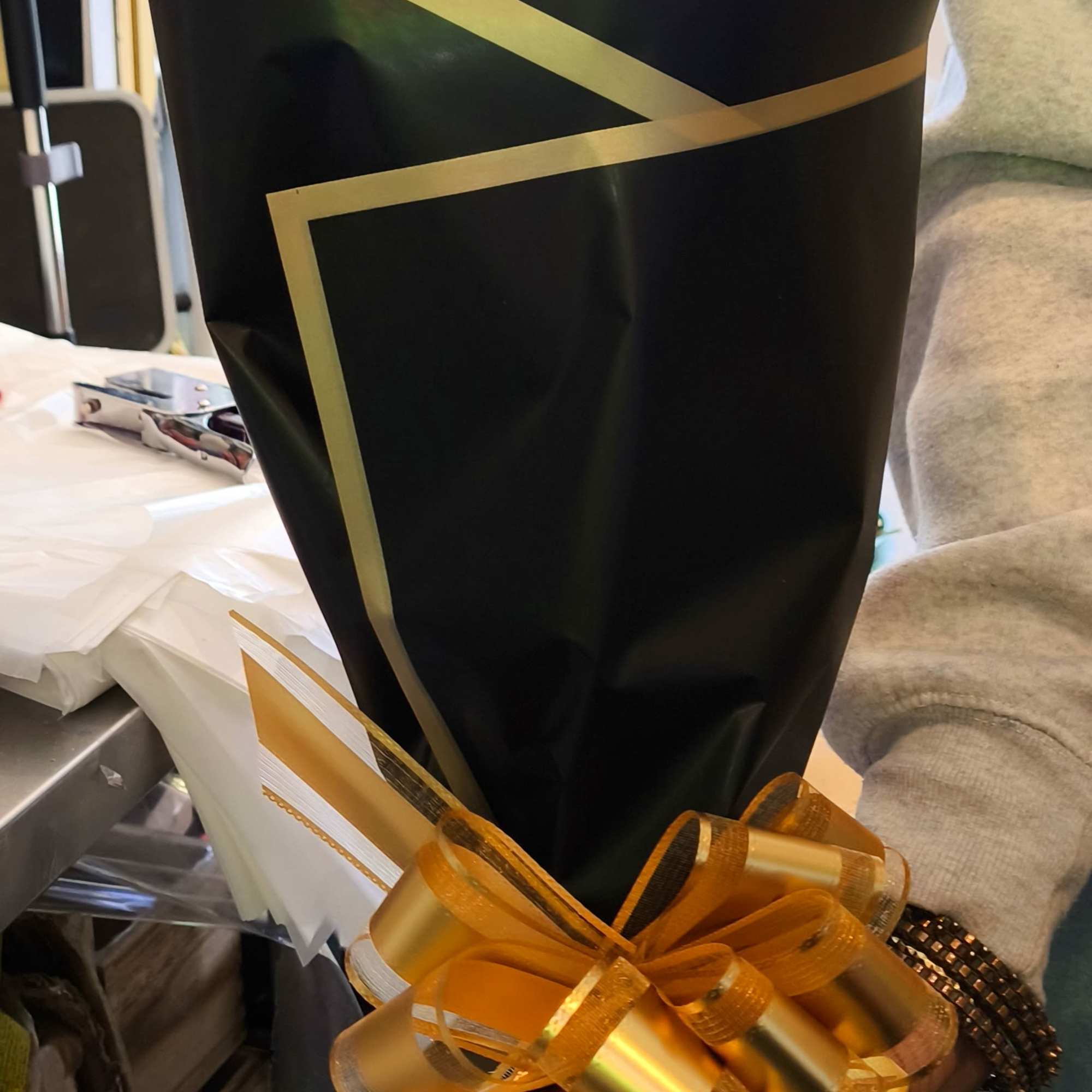Wrapped bouquet with black paper and a gold ribbon bow
