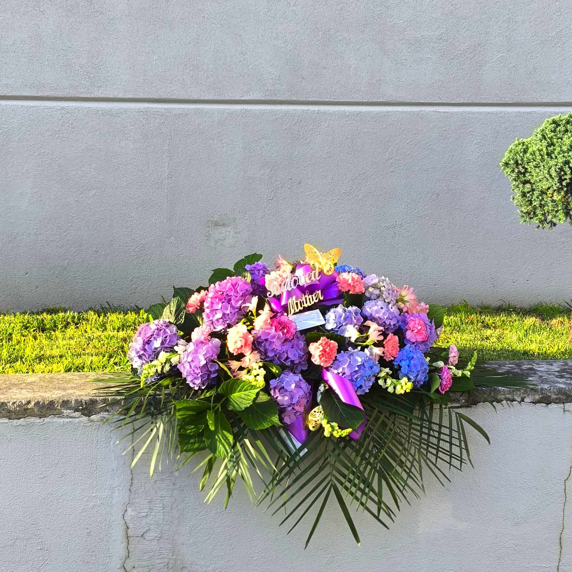 Large purple and pink floral arrangement with a ribbon and butterfly accents