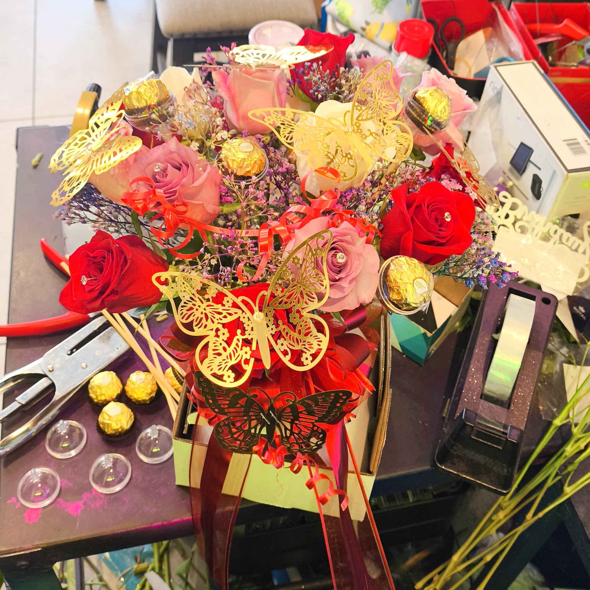 Bouquet of pink and red roses with butterfly decorations and chocolates