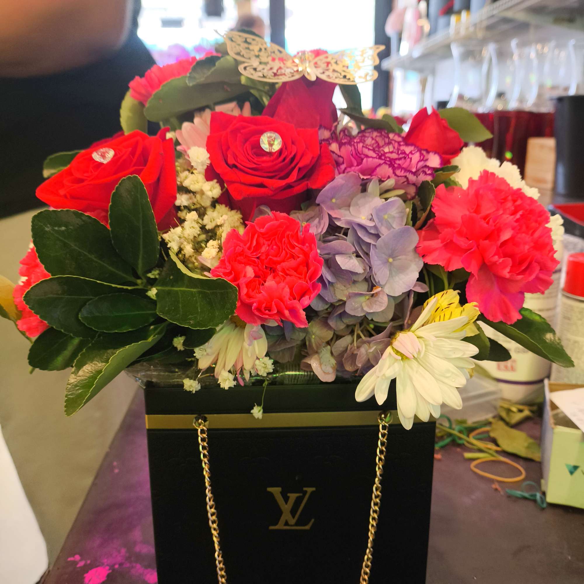 Mixed bouquet of red roses, pink carnations, and lavender hydrangea in a black gift box