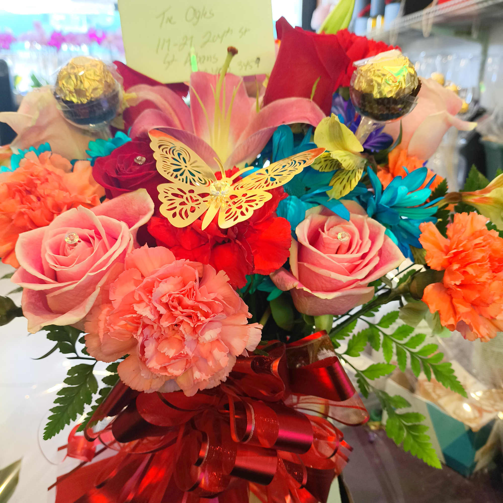 Colorful bouquet of roses, lilies, and carnations with a red ribbon bow