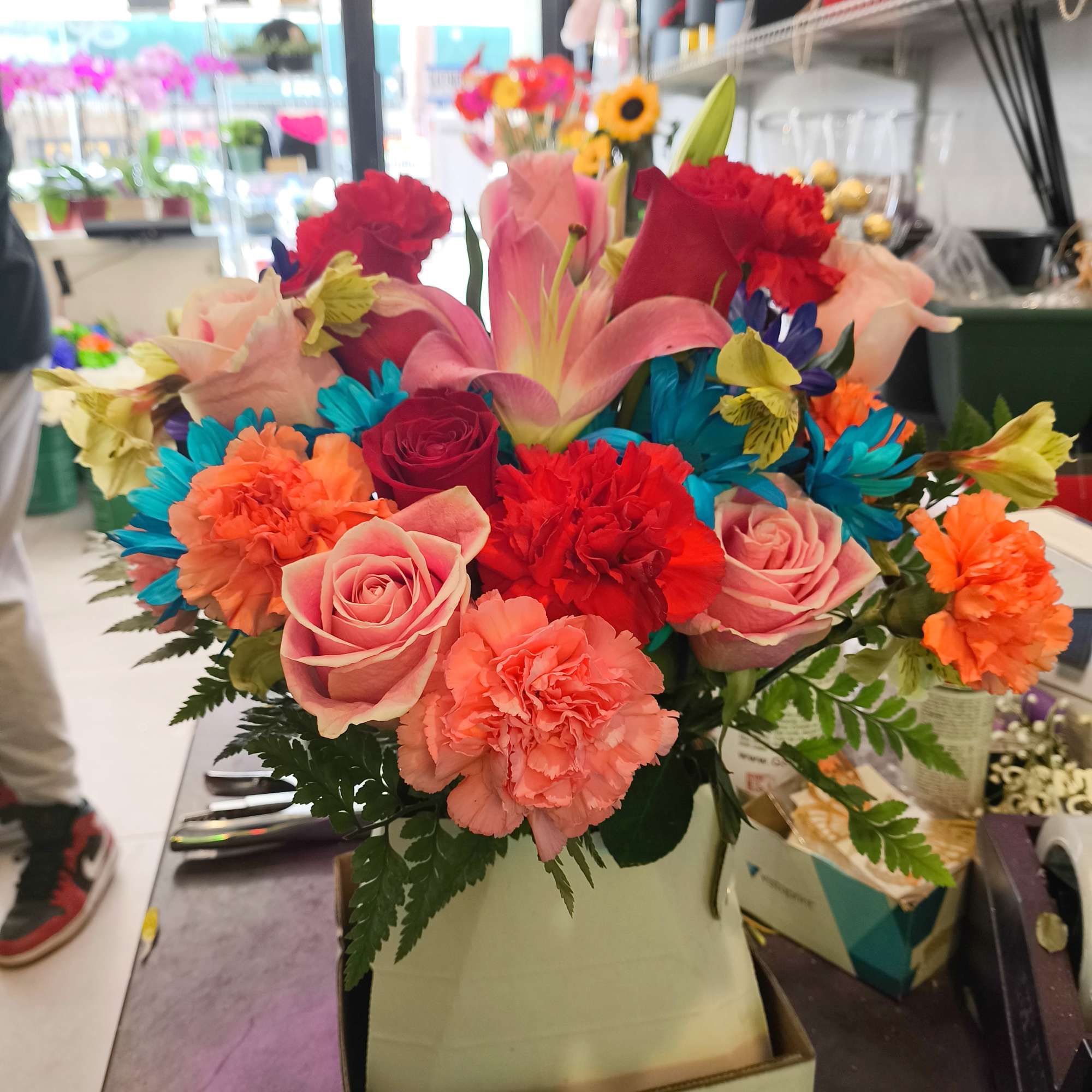 Bright mixed bouquet in a box with roses, lilies, and carnations
