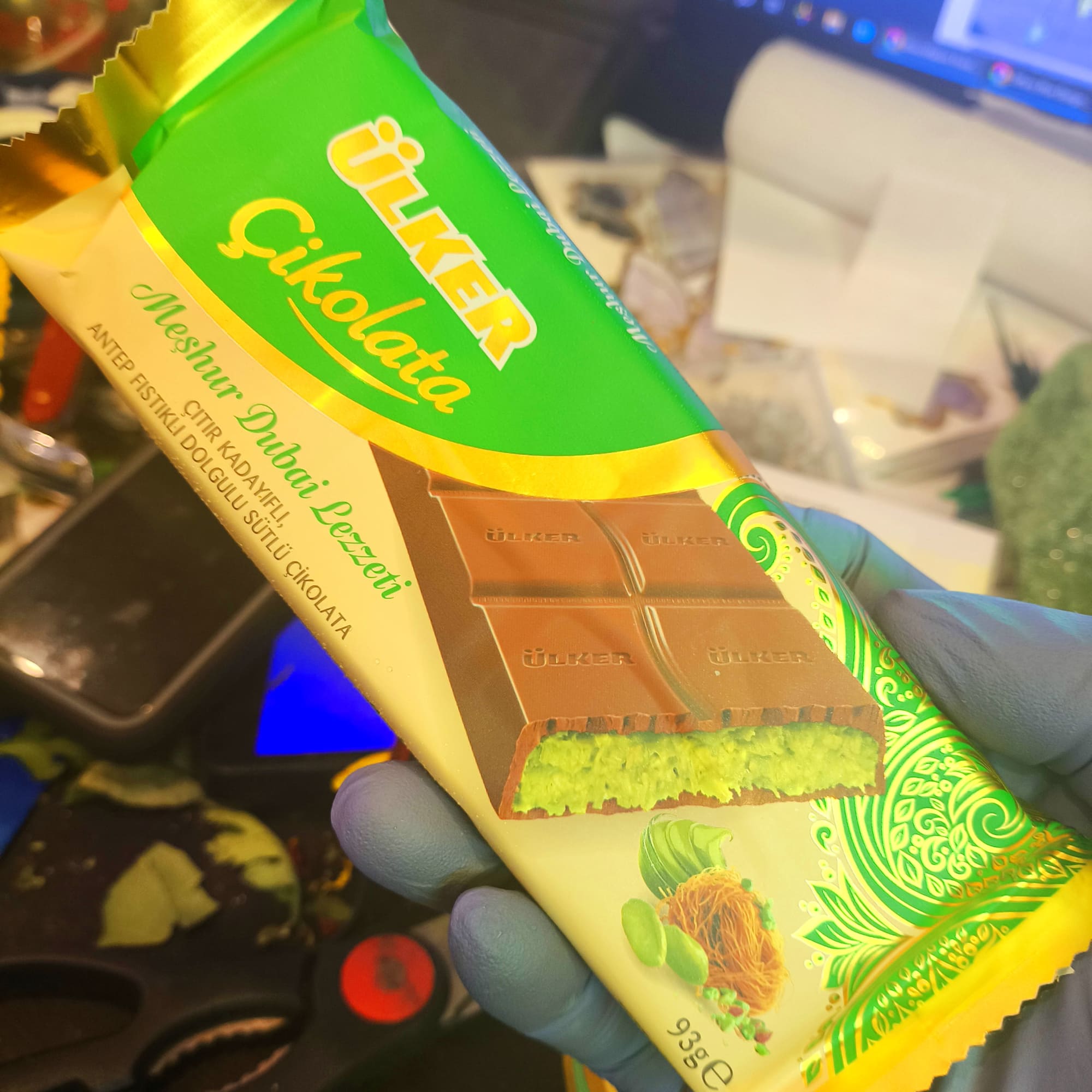 Hand holding a wrapped chocolate bar with green and gold packaging