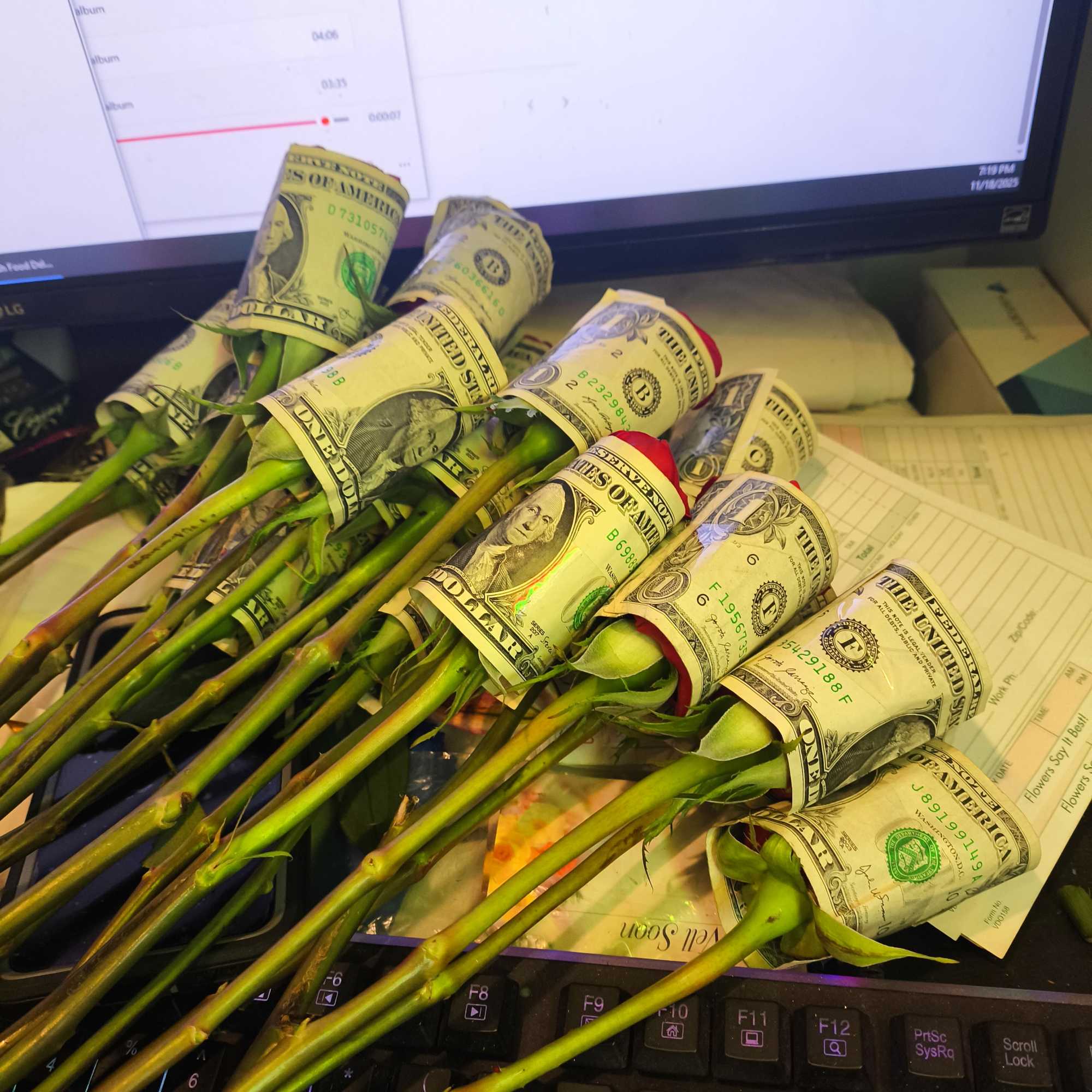 Bouquet of roses wrapped in dollar bills on a computer keyboard