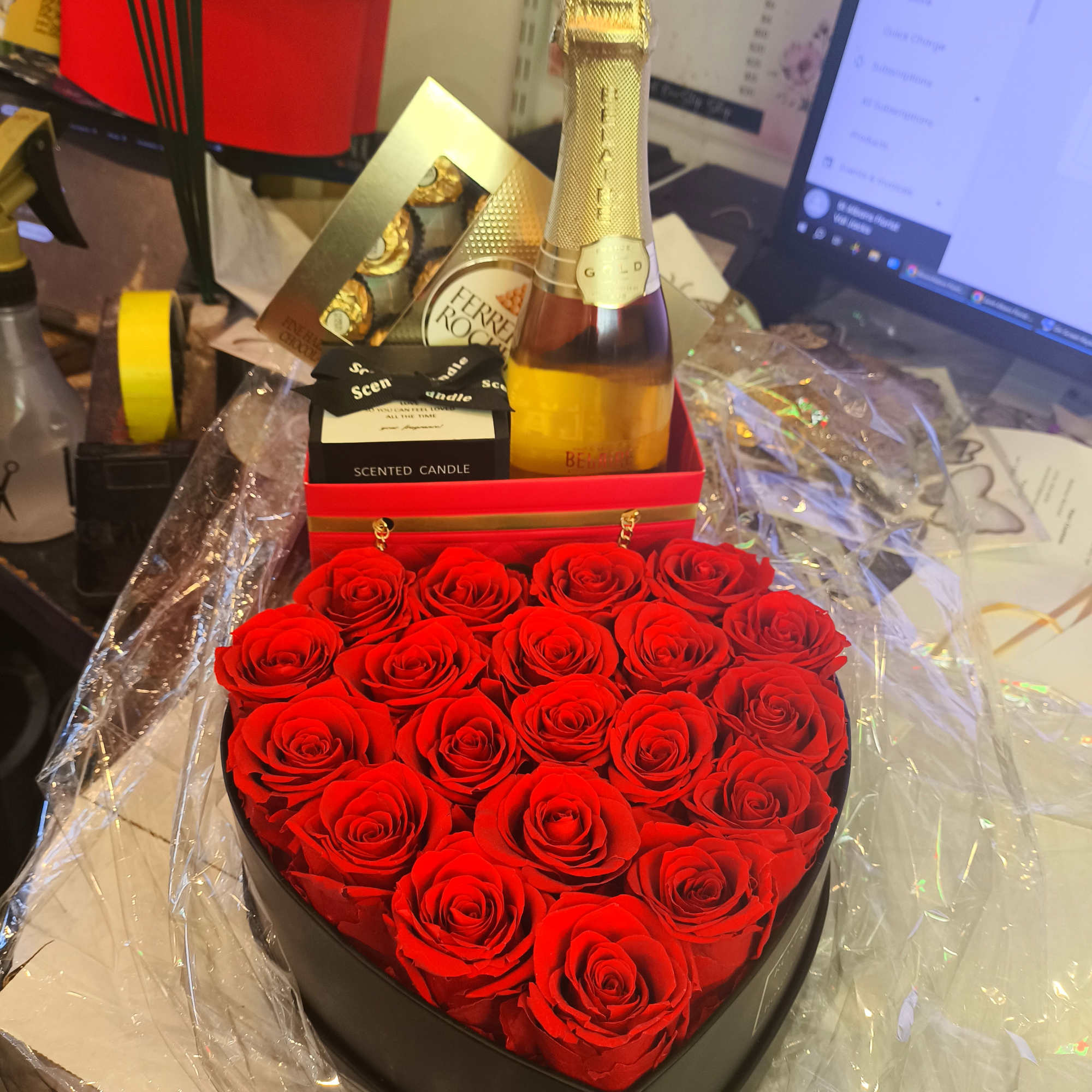 Heart-shaped box of red roses with a champagne bottle and candle gift set
