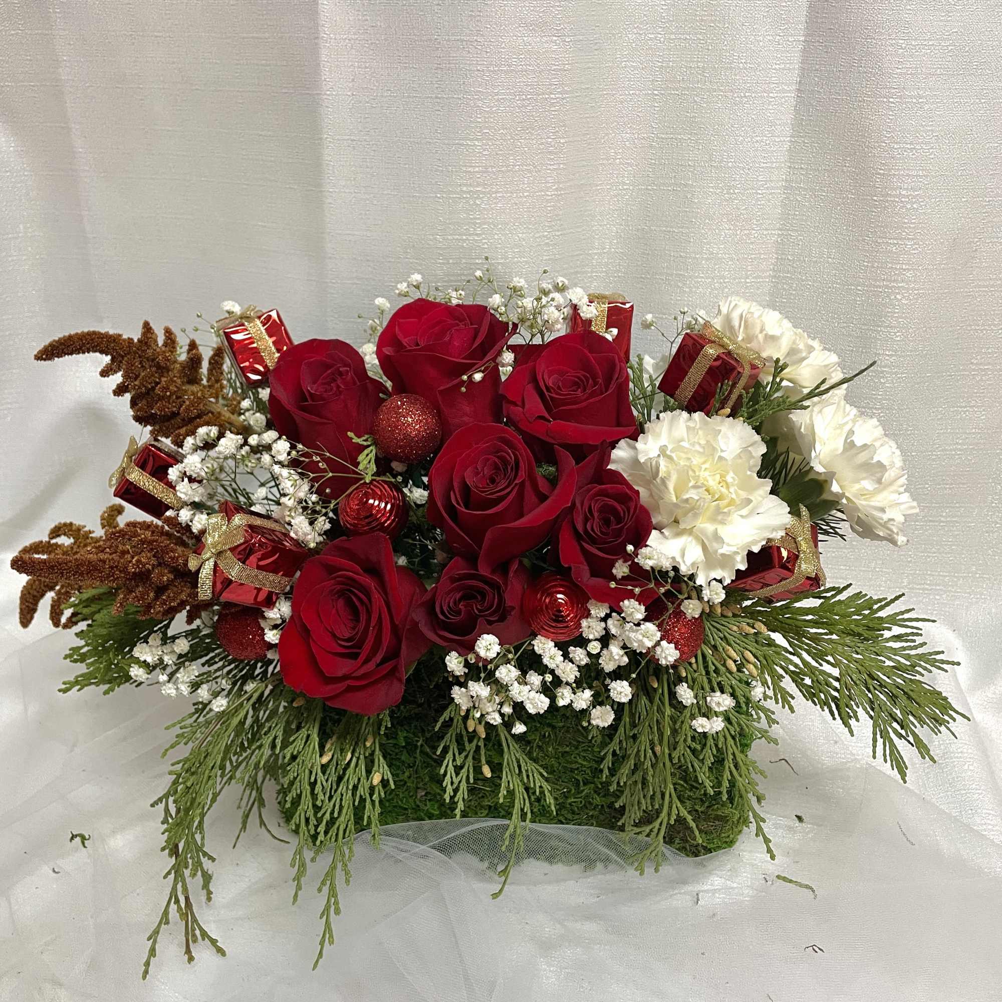 An enchanting holiday arrangement set in a lovely green moss purse (with