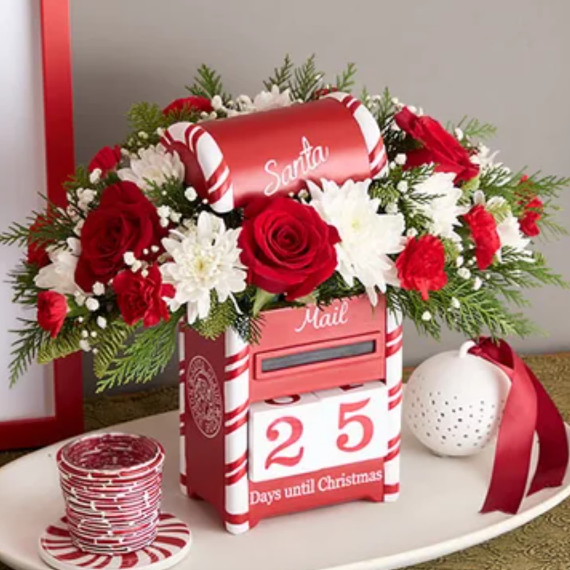 Red and white floral arrangement on a Santa mailbox display with a countdown block