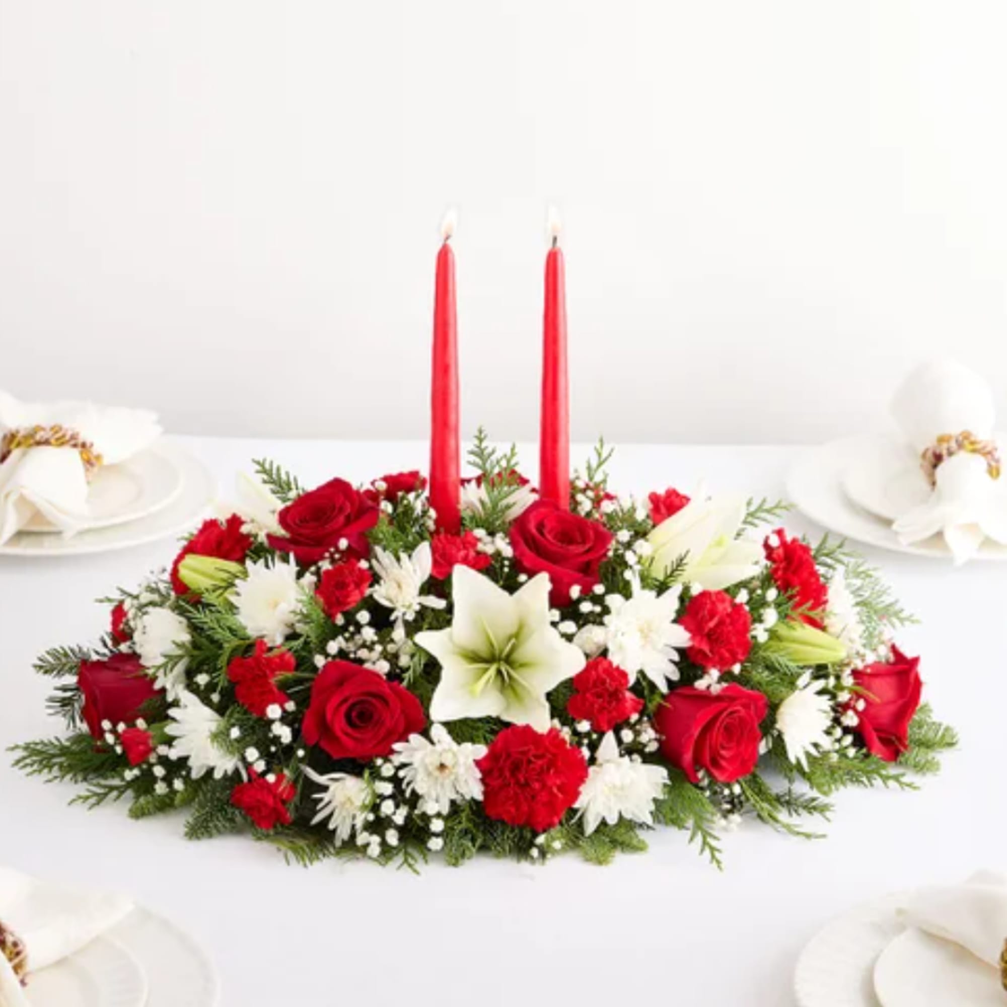 Red and white floral centerpiece with two red taper candles