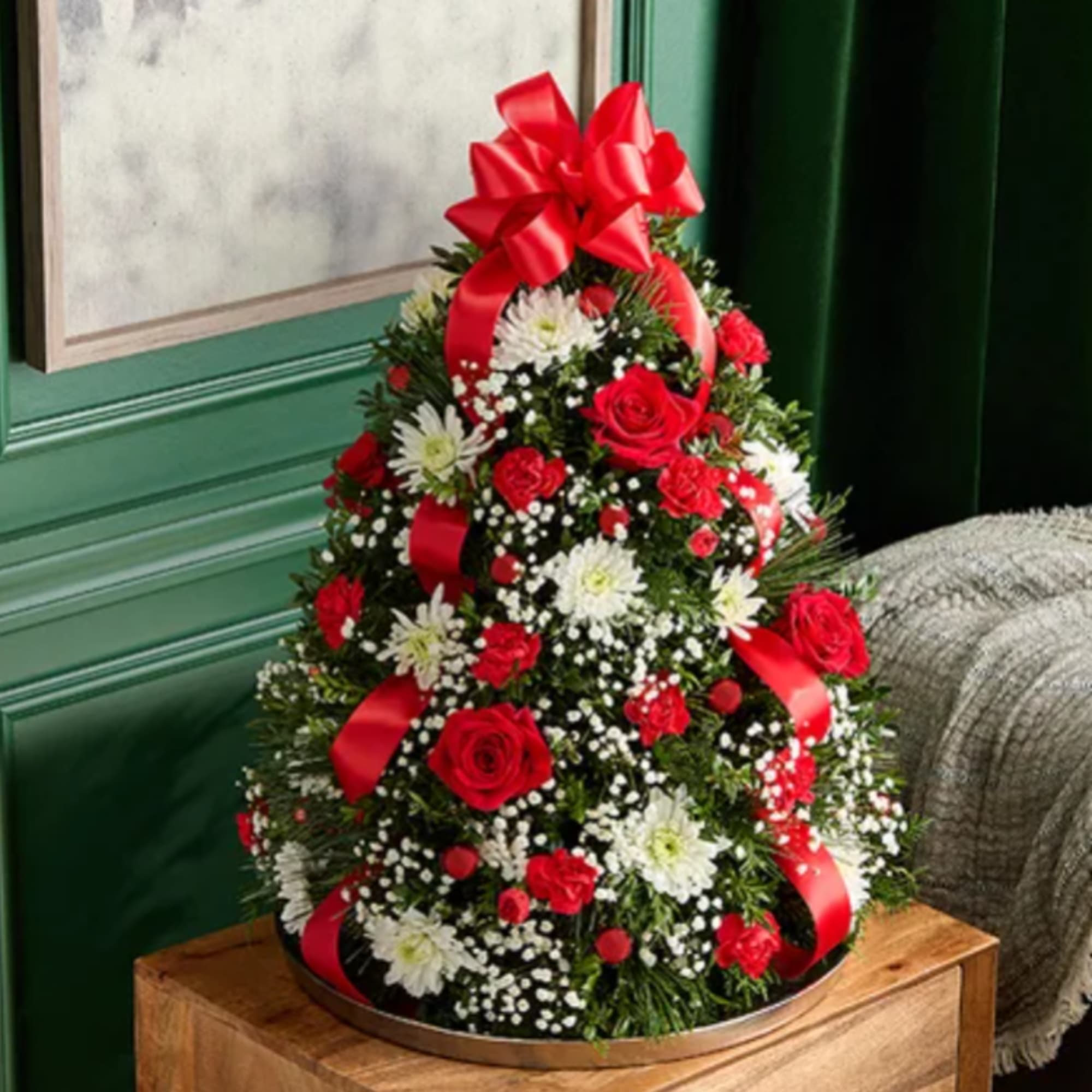 Cone-shaped floral arrangement with red roses, white daisies, and red ribbon