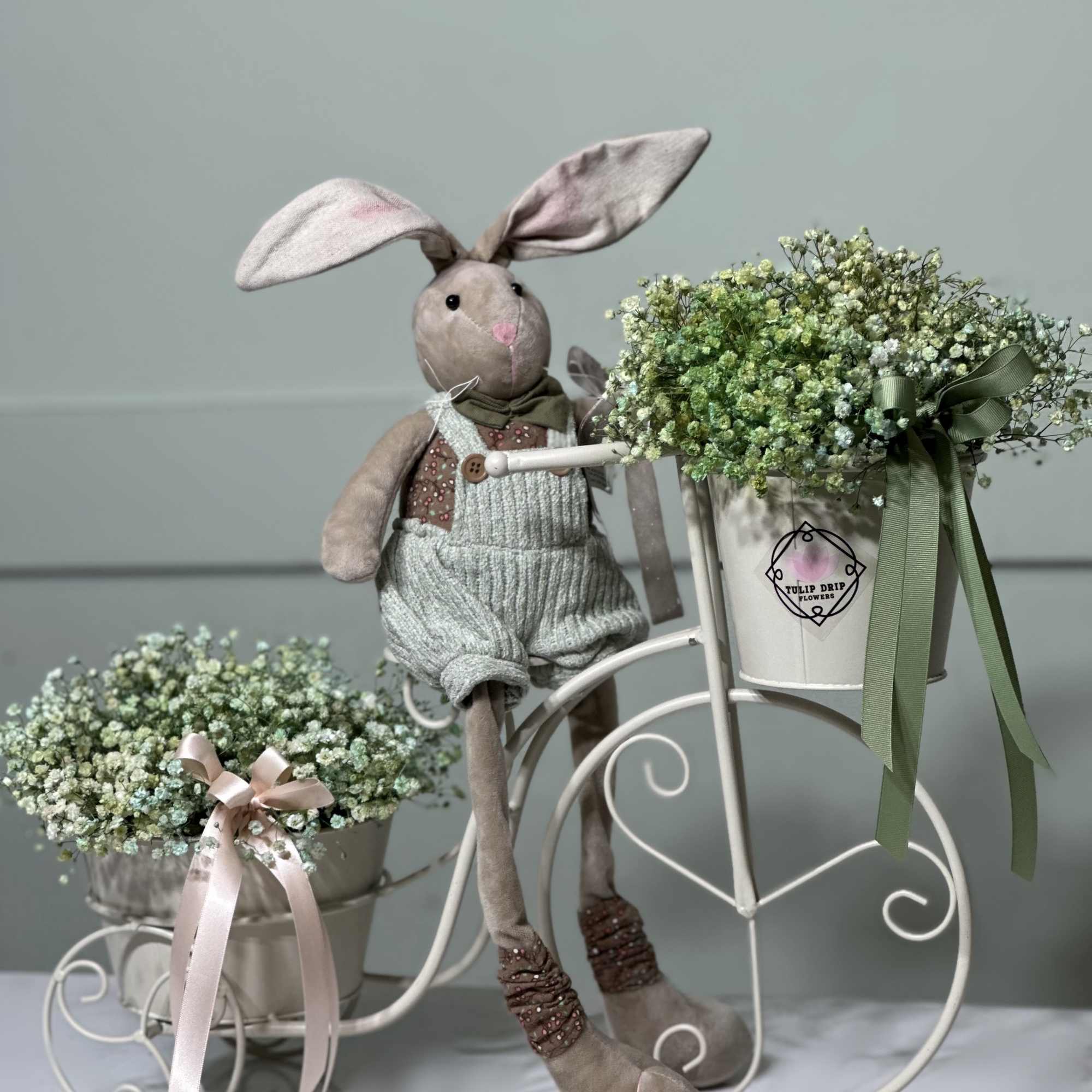 Adorable Baby's Breath adorning a charming bicycle alongside a cuddly stuffed bunny
