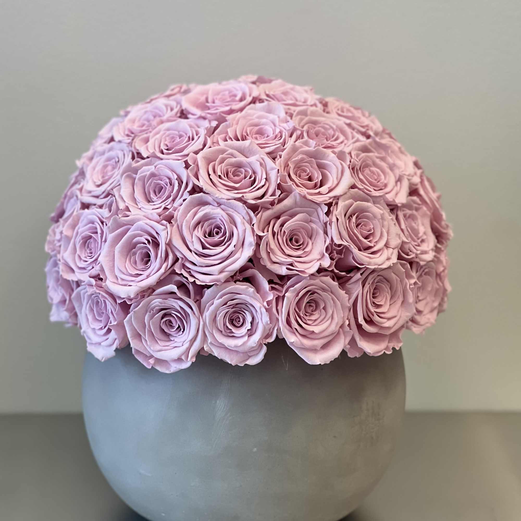 Round bouquet of pale pink roses in a gray vase