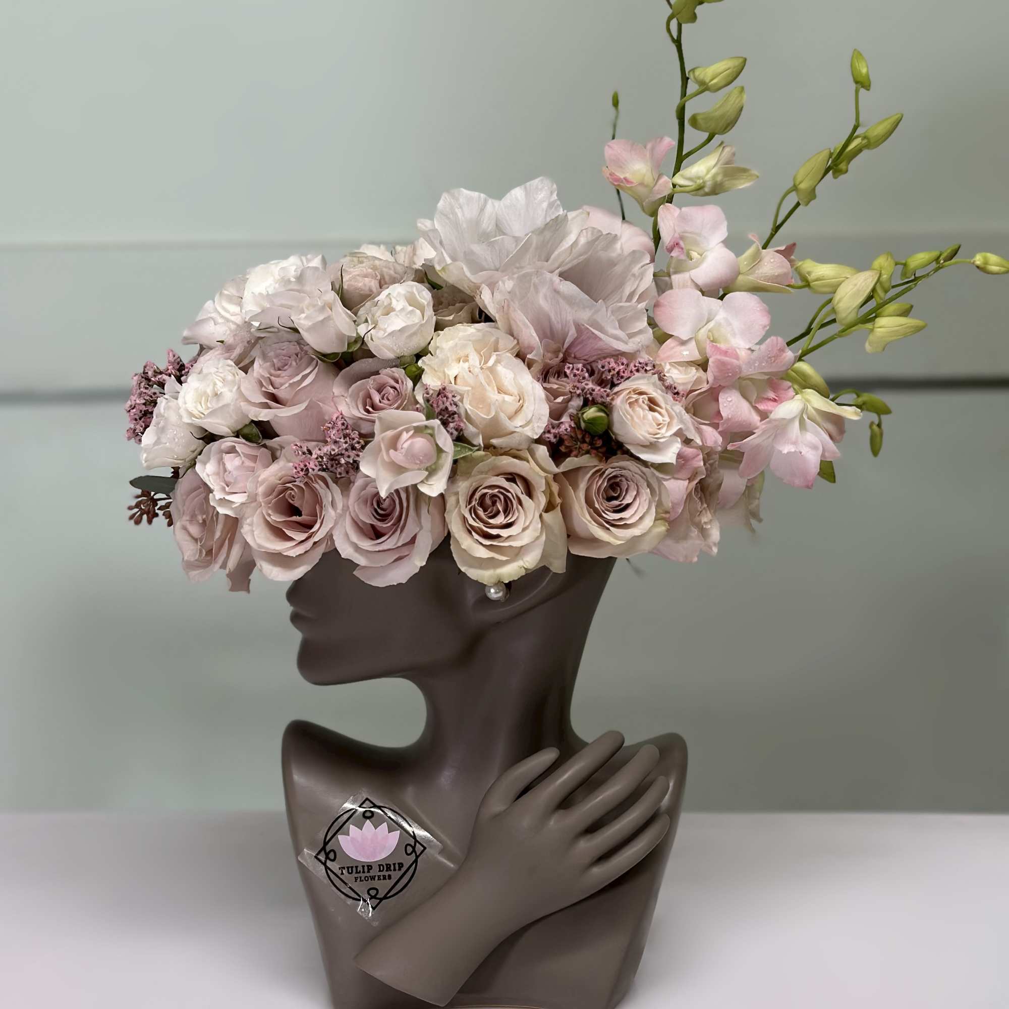 Pink and white floral arrangement in a sculptural bust vase