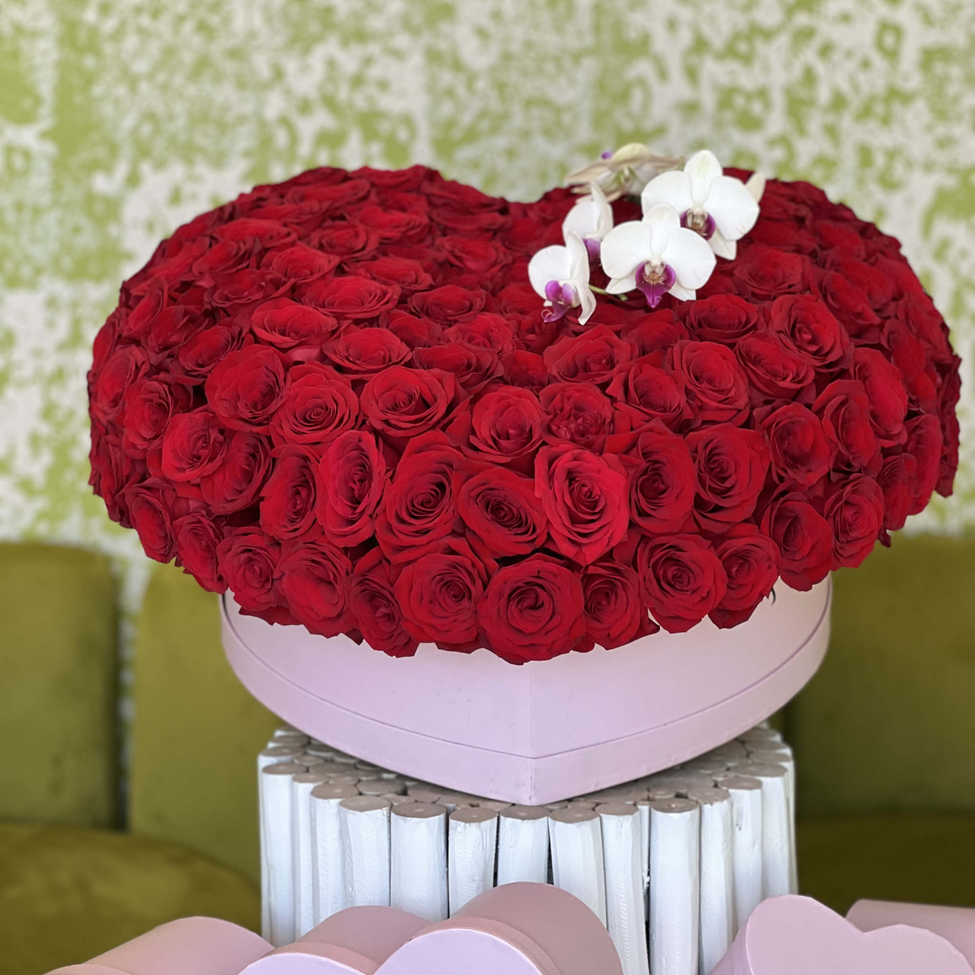 Heart-shaped box of red roses with white orchids
