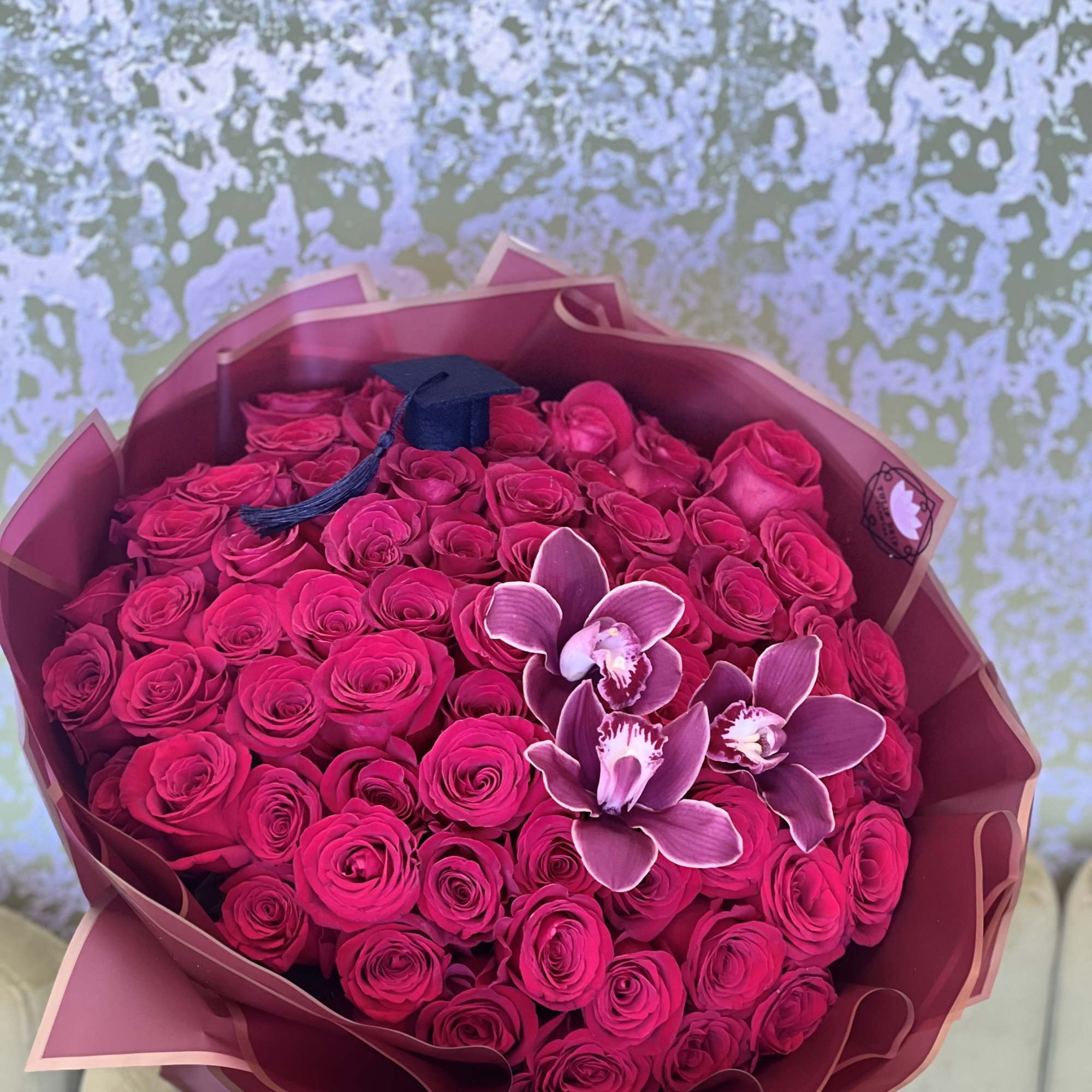 Bouquet of hot pink roses with orchid accents in pink wrap