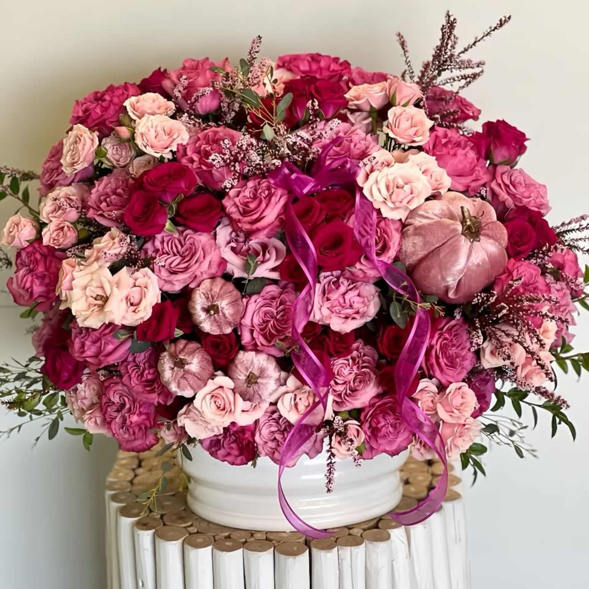 Large pink and magenta rose arrangement in a white vase