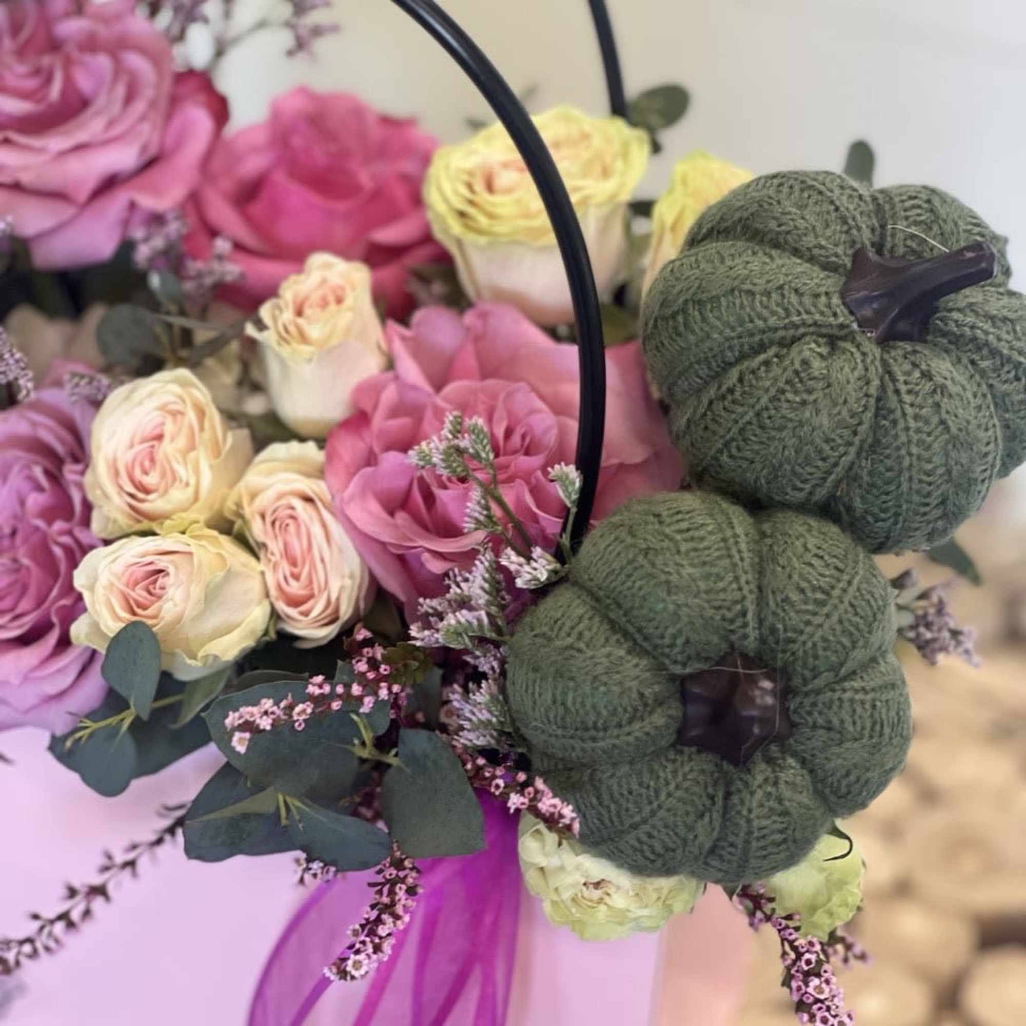 Pink and cream roses in a basket with two knitted pumpkins