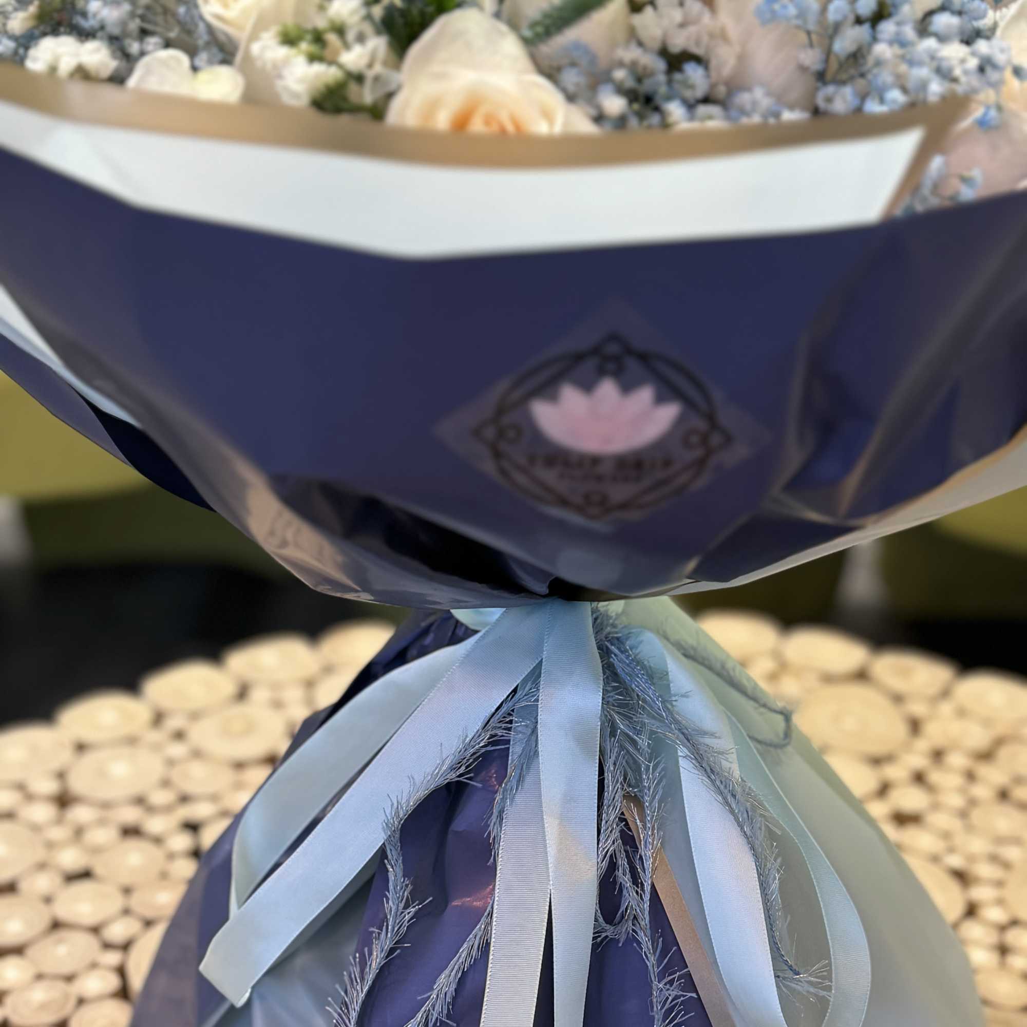 Bouquet of white roses and blue baby's breath wrapped in blue paper