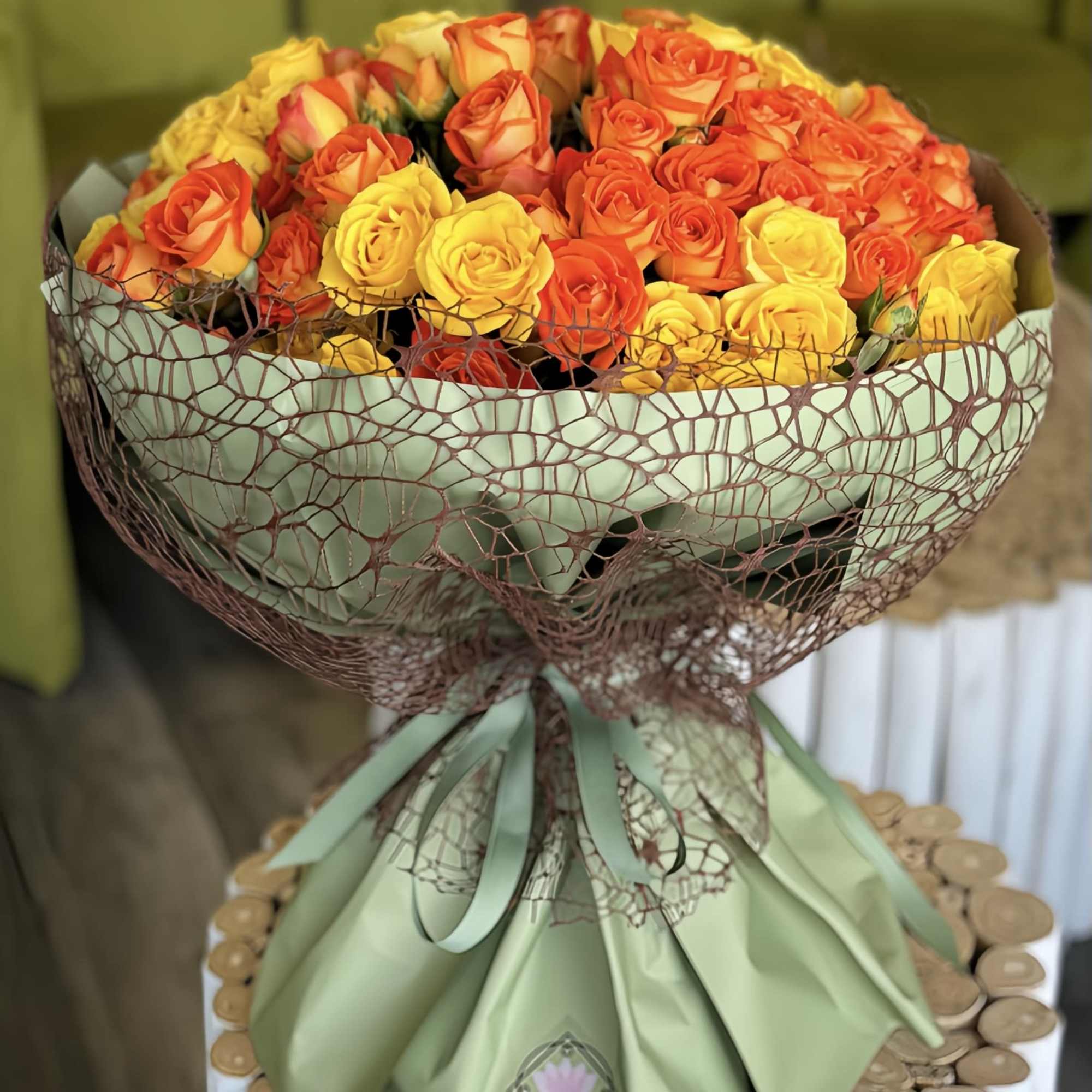 Bouquet of orange and yellow roses wrapped in green paper