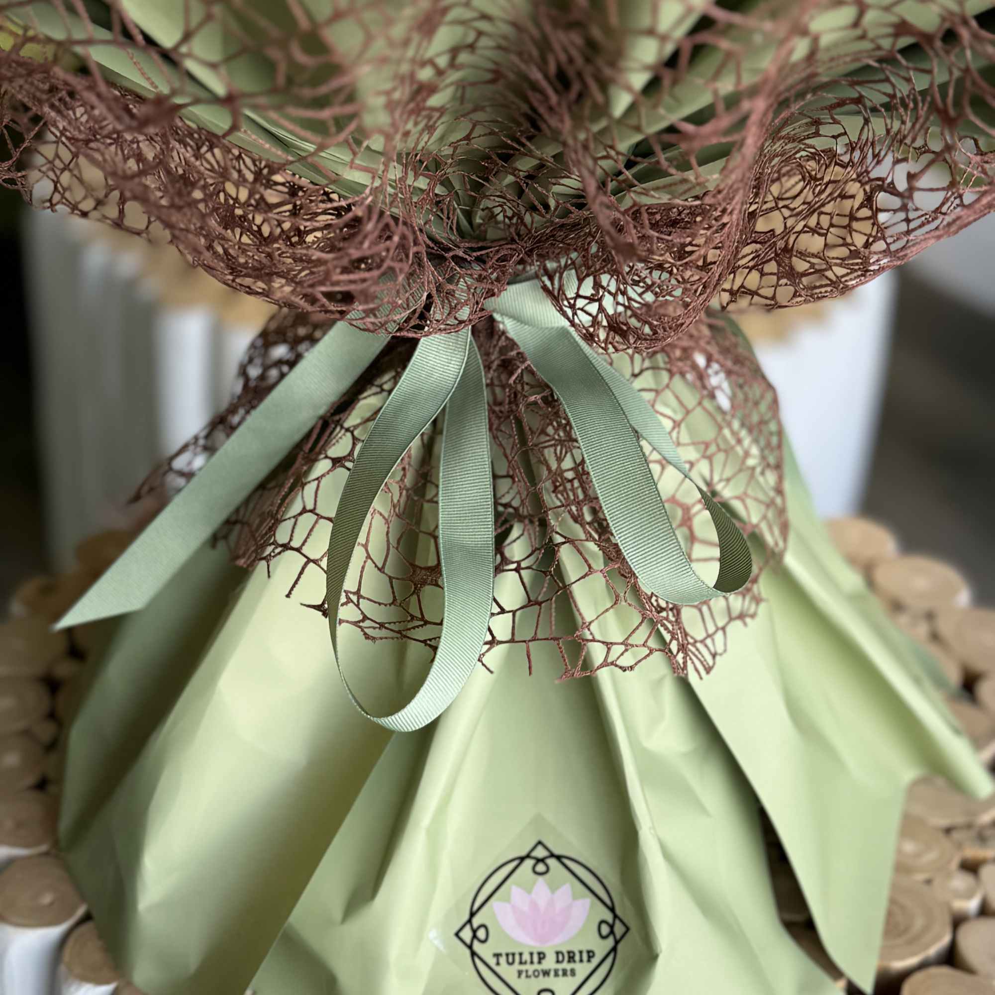 Wrapped bouquet with green paper and brown mesh ribbon